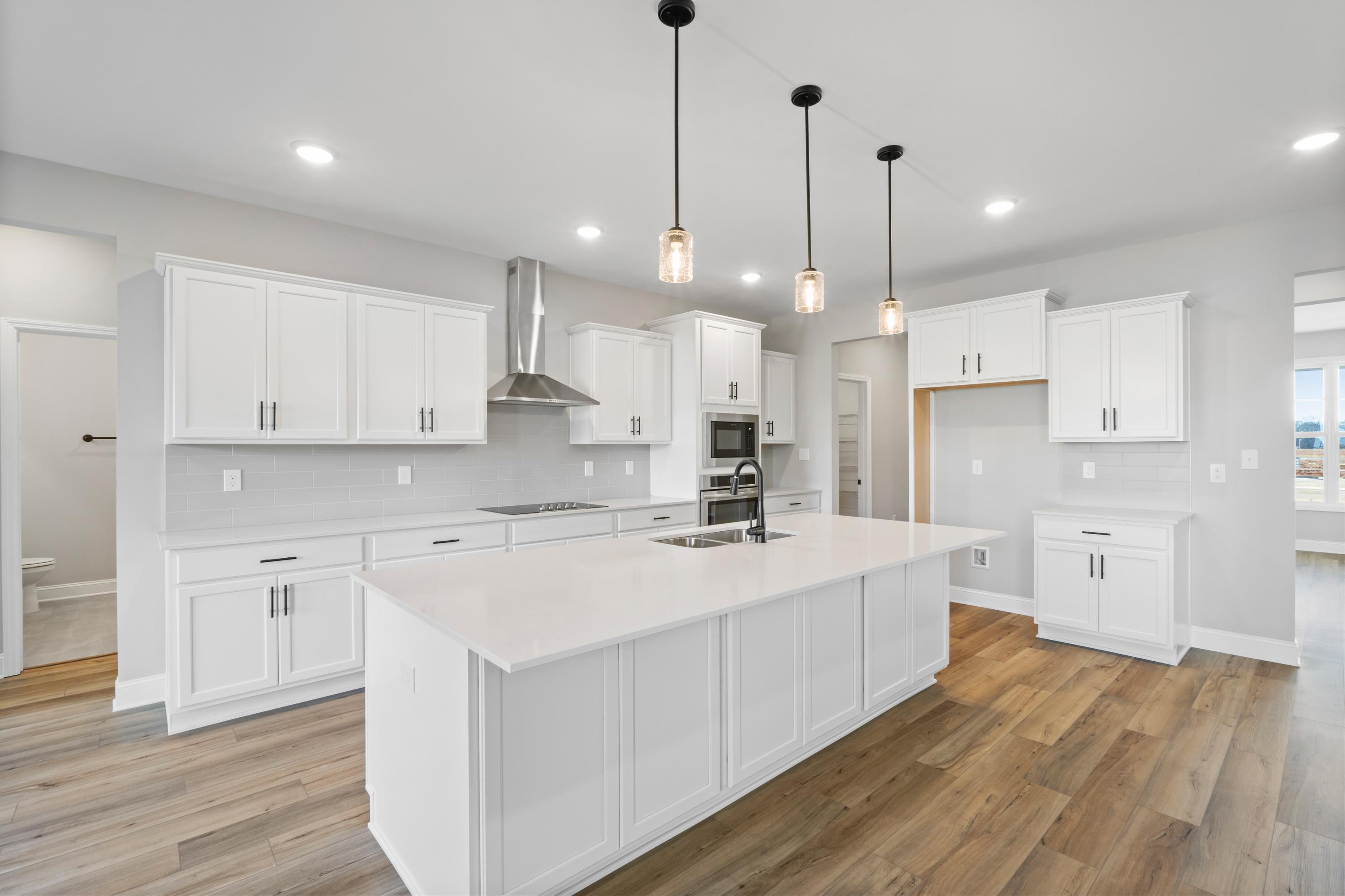 Spacious Valencia kitchen by Davidson Homes featuring white shaker cabinets, quartz island sink, and stainless appliances