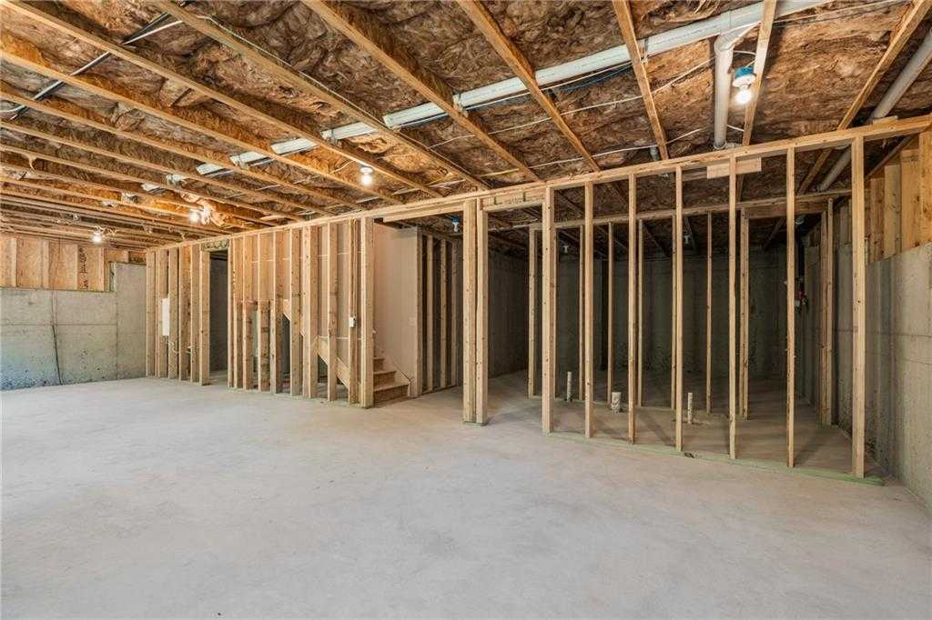 Unfinished basement framing with wooden studs, stairs, and exposed insulation in Hickory B 5-bedroom home, Davidson Homes, Riverwood, Dallas, GA