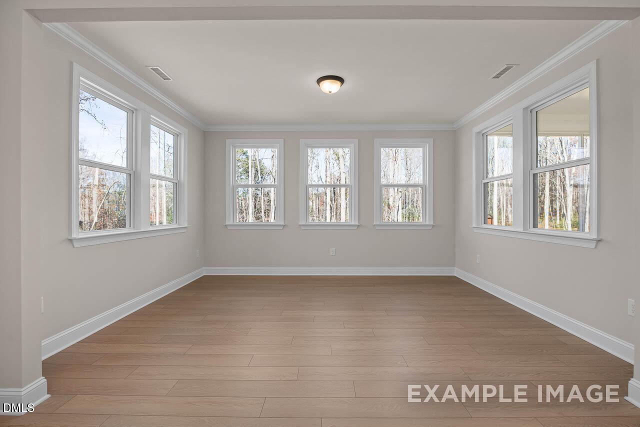 Bright sunlit great room with large windows, hardwood floors, and light gray walls in Davidson Homes The Crawford D, Angier, NC