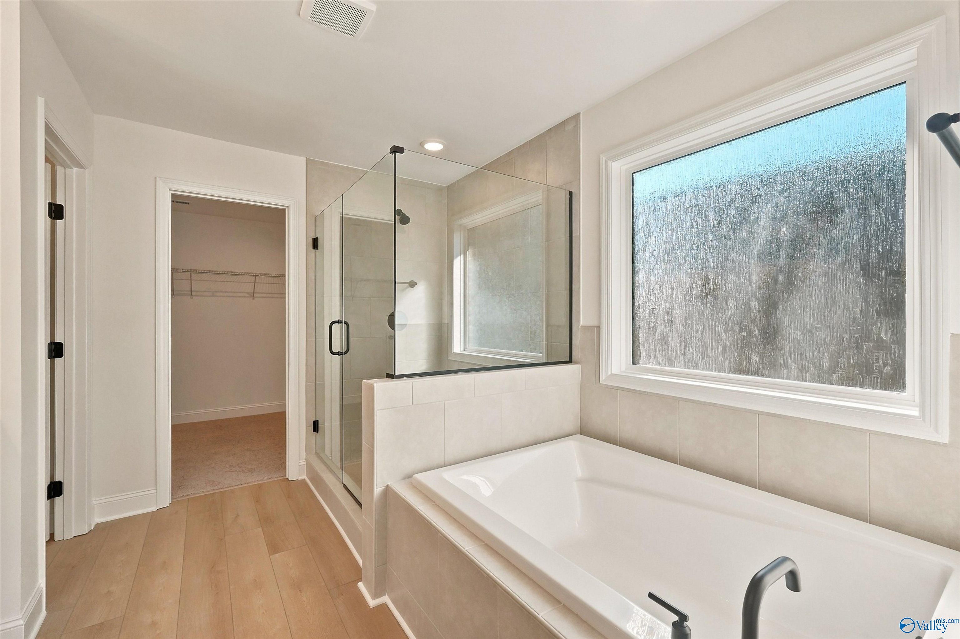 Primary bathroom with soaking tub, glass-enclosed shower, and walk-in closet in The Chelsea C home, Creek Grove, New Market.