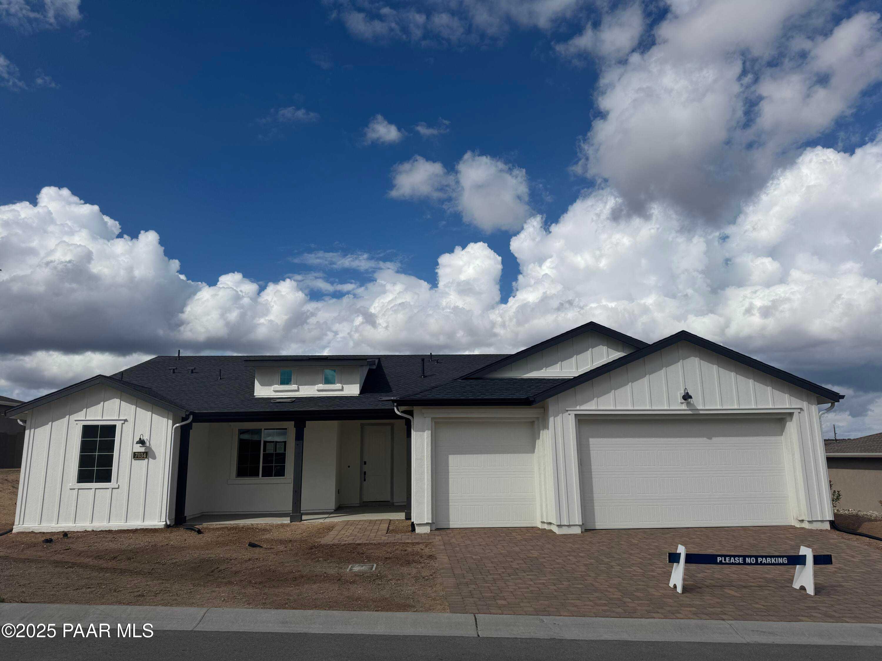 Modern single-story home with 3-car garage, white siding, black trim, and desert landscaping in Westwood, Prescott, Arizona