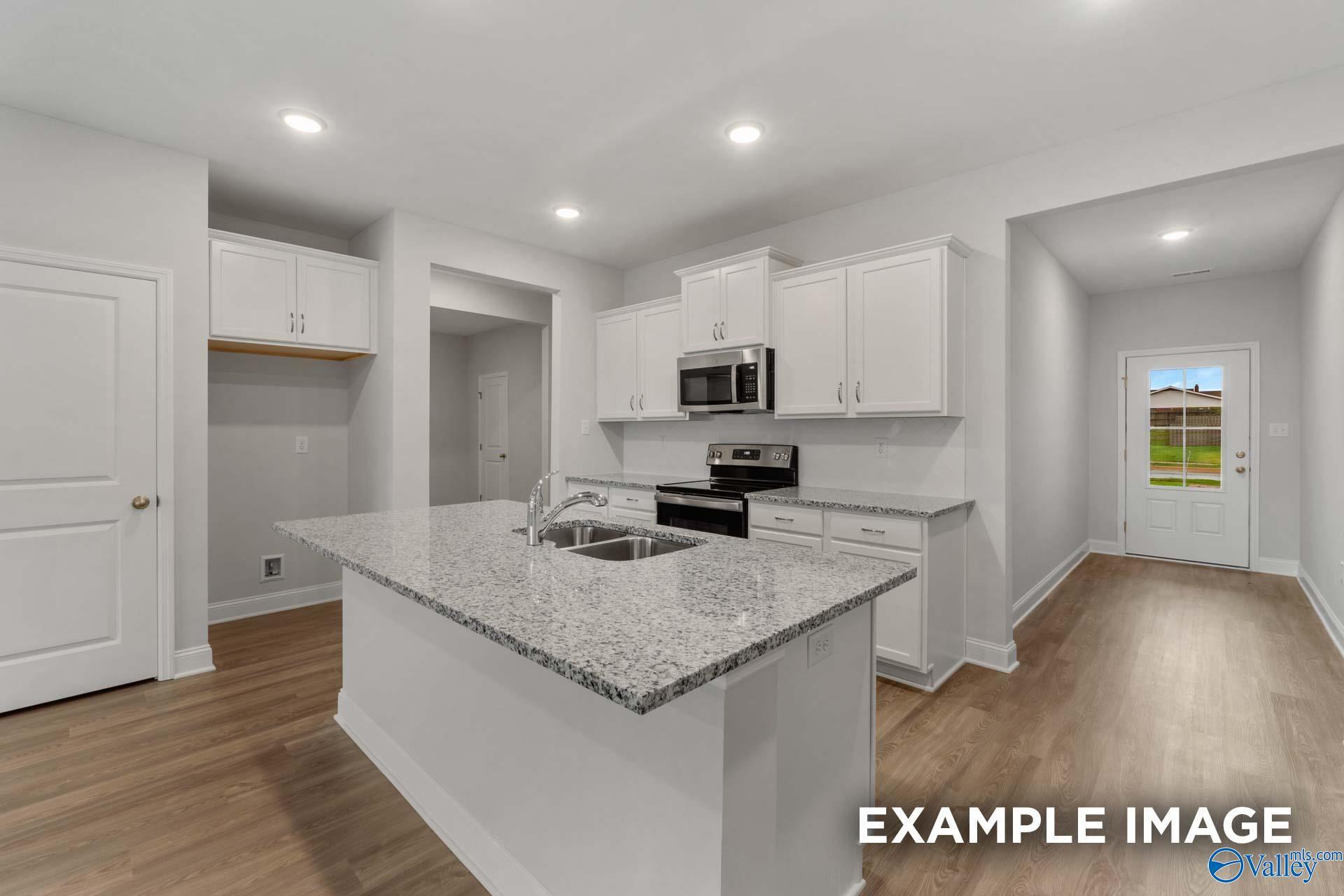 Modern open-concept kitchen with white cabinets, granite island, stainless appliances in Cumberland B by Davidson Homes, Decatur, AL