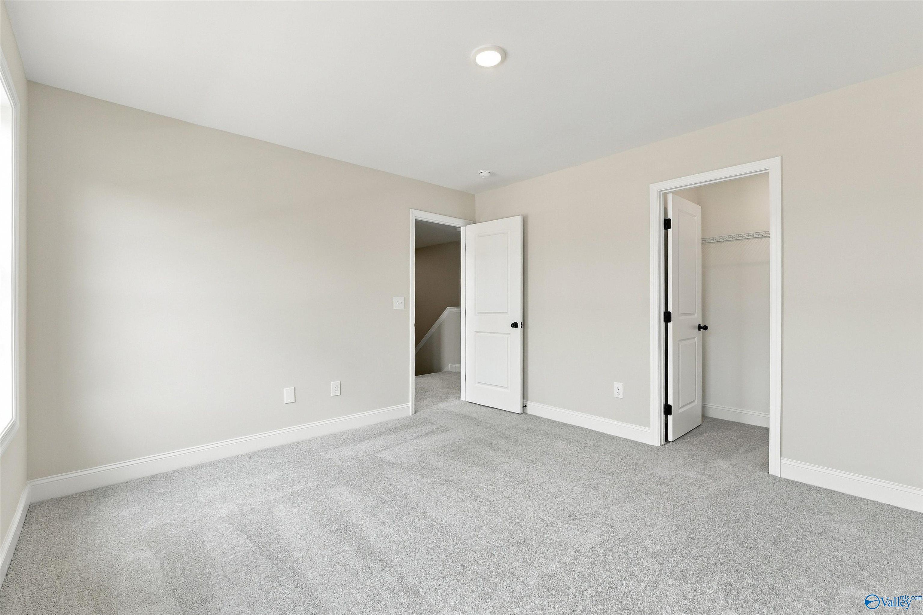 Bright carpeted bedroom with walk-in closet and natural light in Davidson Homes' The Shelby A, The Meadows, Athens, Alabama