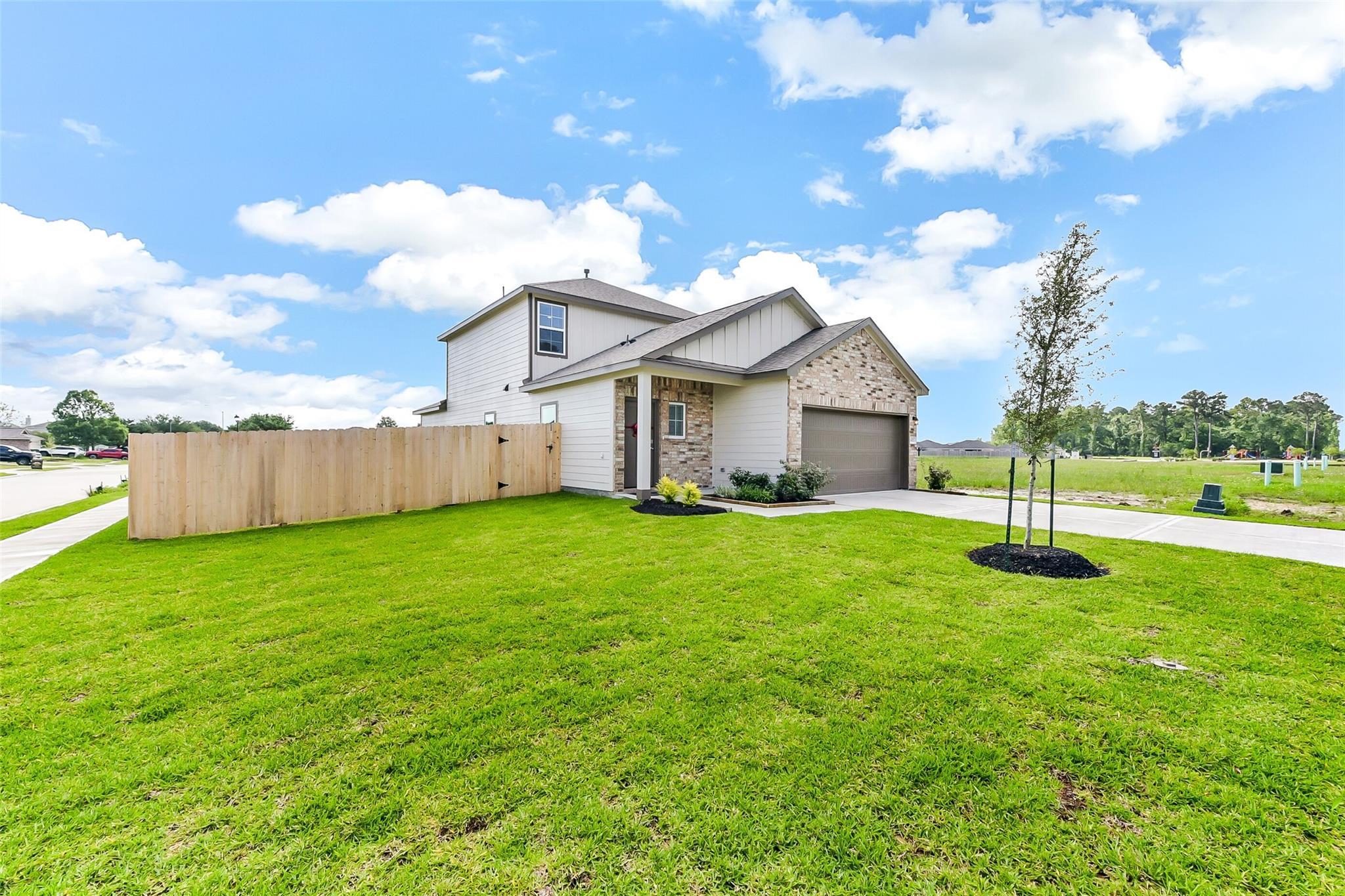 Modern 2-story Sabine F home exterior with stone accents, 2-car garage, front porch, and green lawn in The Villages at WestPointe, Dayton, Texas