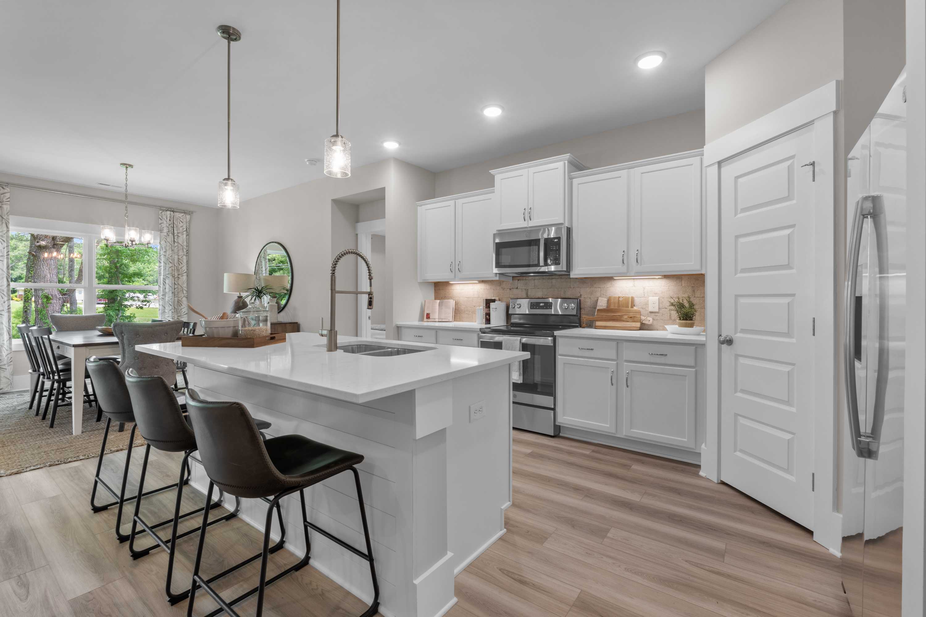 Open-concept white kitchen in The Highlands, Arab AL with quartz island, pendant lights, hardwood floors and dining area
