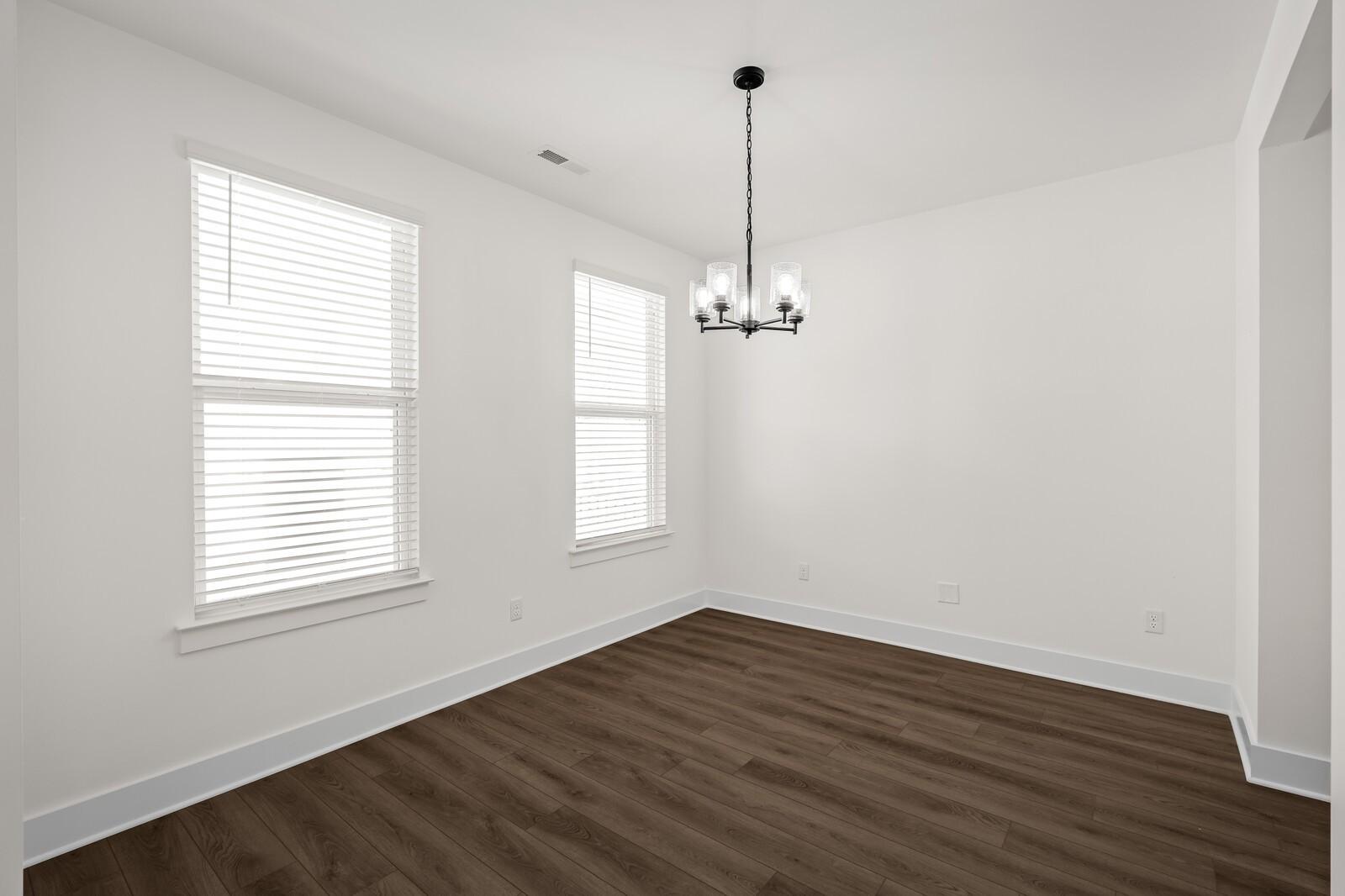 Bright dining area with modern chandelier and wood-look flooring in The Willow floor plan, Woods Crossing, Gallatin, TN.