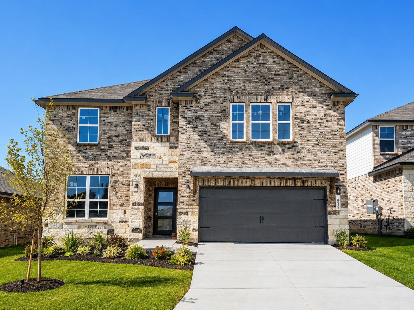 Two-story brick and stone home exterior by Davidson Homes at Bricewood in San Antonio, TX with a two-car garage.