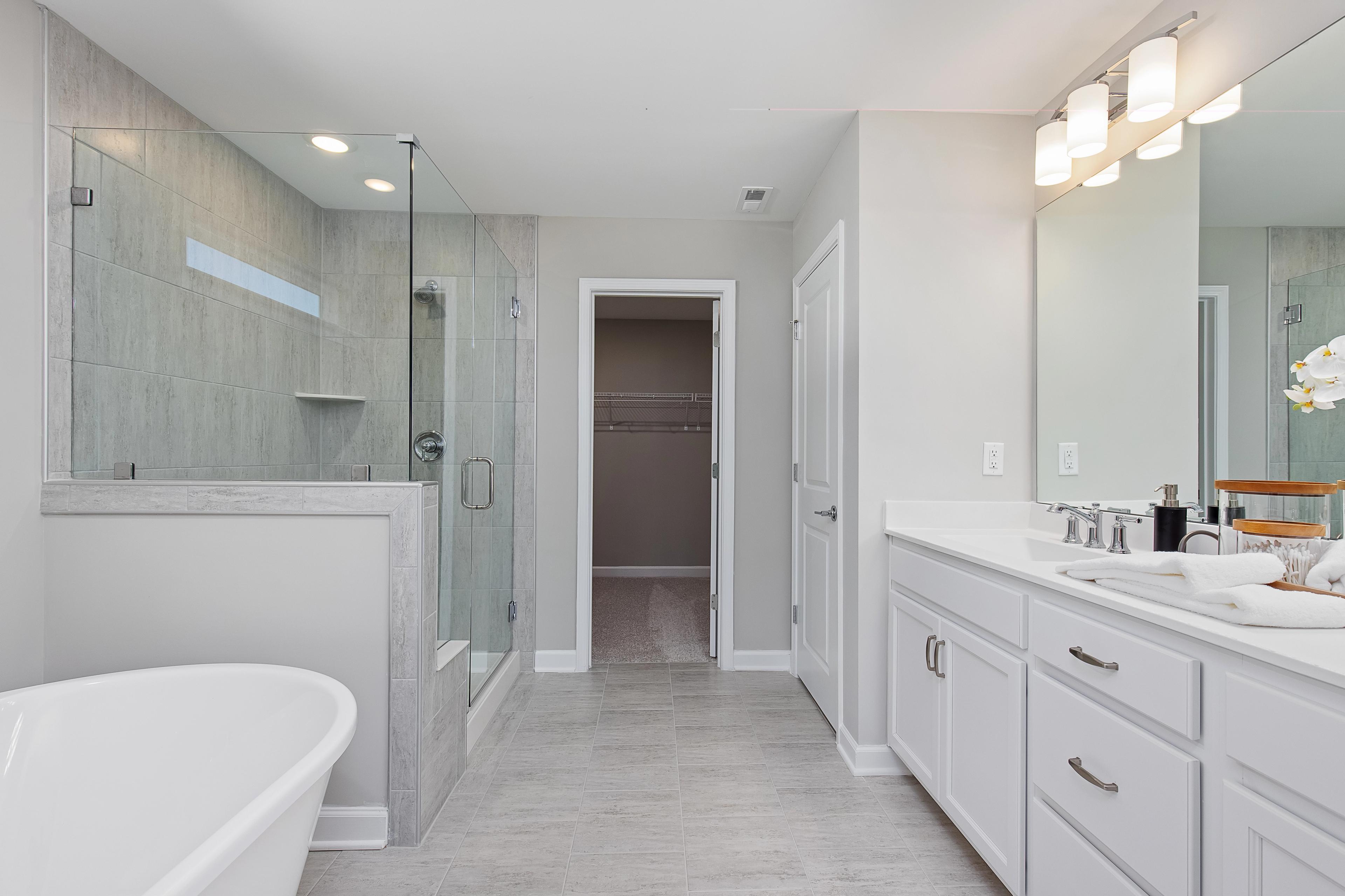 Spacious primary bathroom at Woodland Crossing in Zebulon NC with freestanding tub, glass shower, double vanity, and walk-in closet