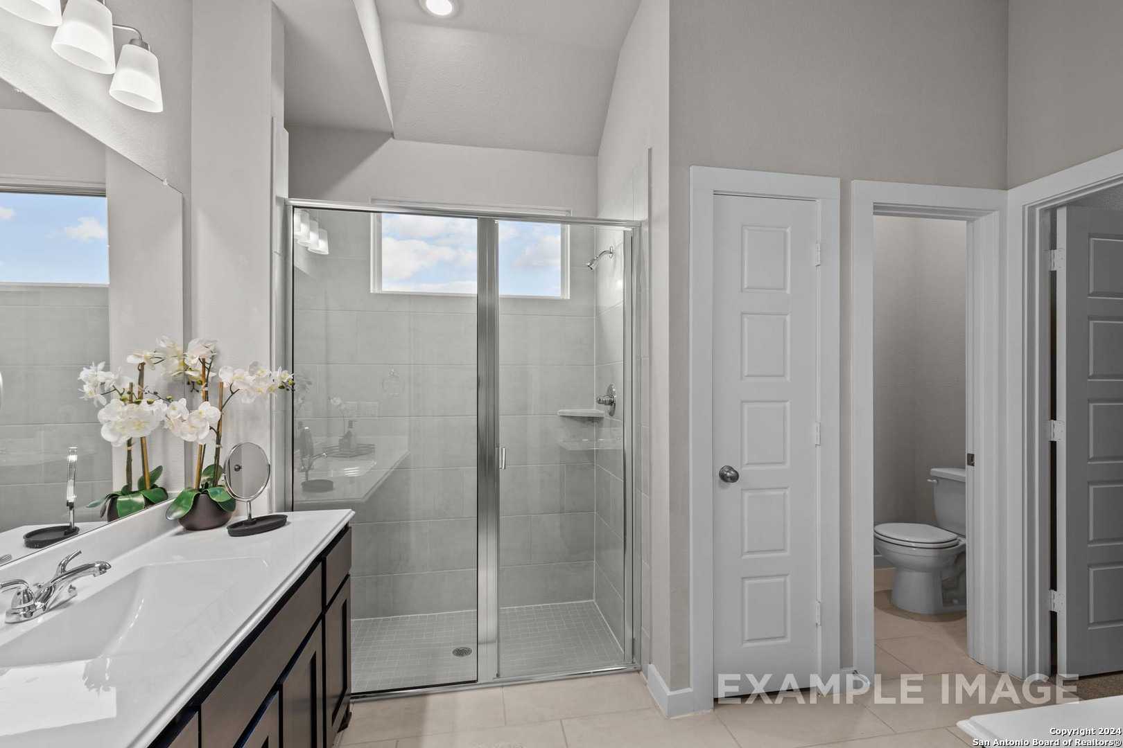 Modern master bathroom with framed glass shower, double vanity, orchids in Davidson Homes The Collin A, Seguin, Texas