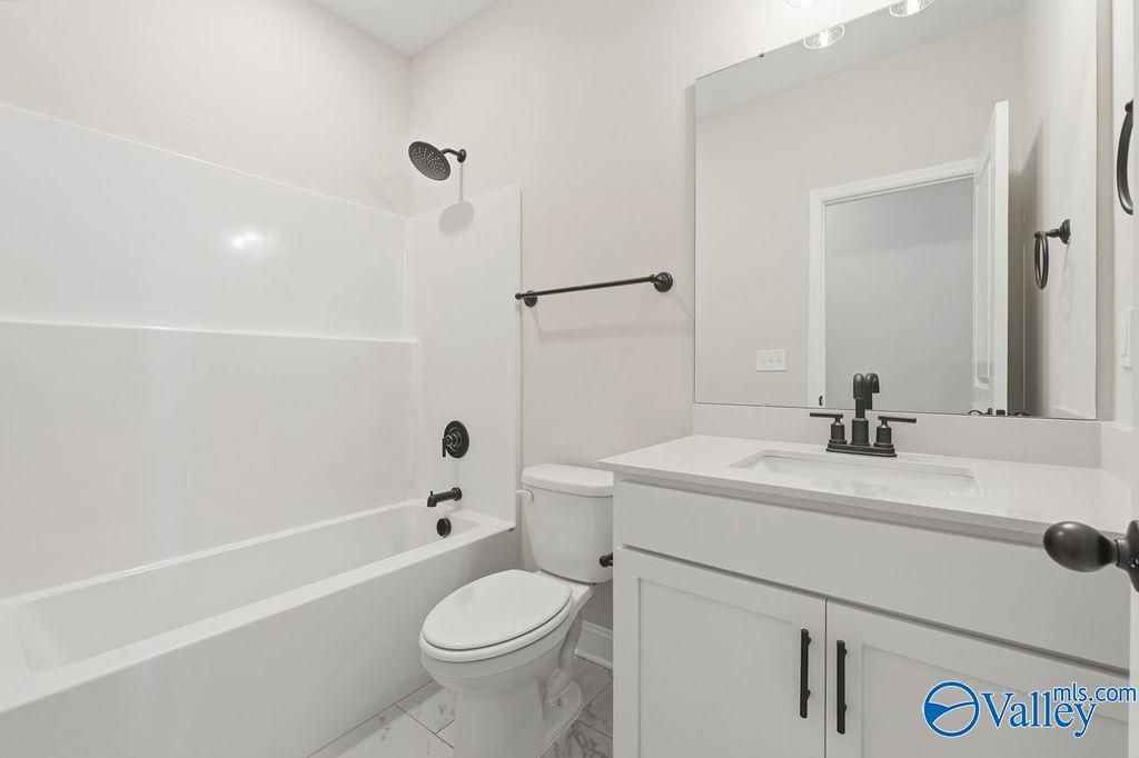 Bright white bathroom with tub-shower combo, single vanity, black fixtures in Davidson Homes The Rockford B, Hartselle, Alabama