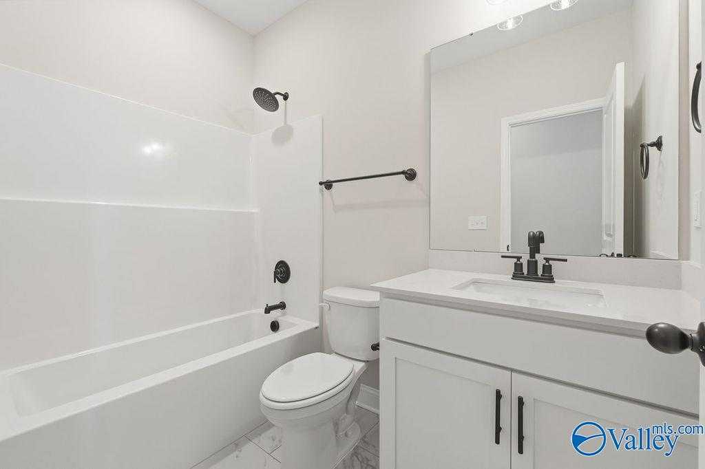 Bright white bathroom with tub-shower combo, single vanity, black fixtures in Davidson Homes The Rockford B, Hartselle, Alabama
