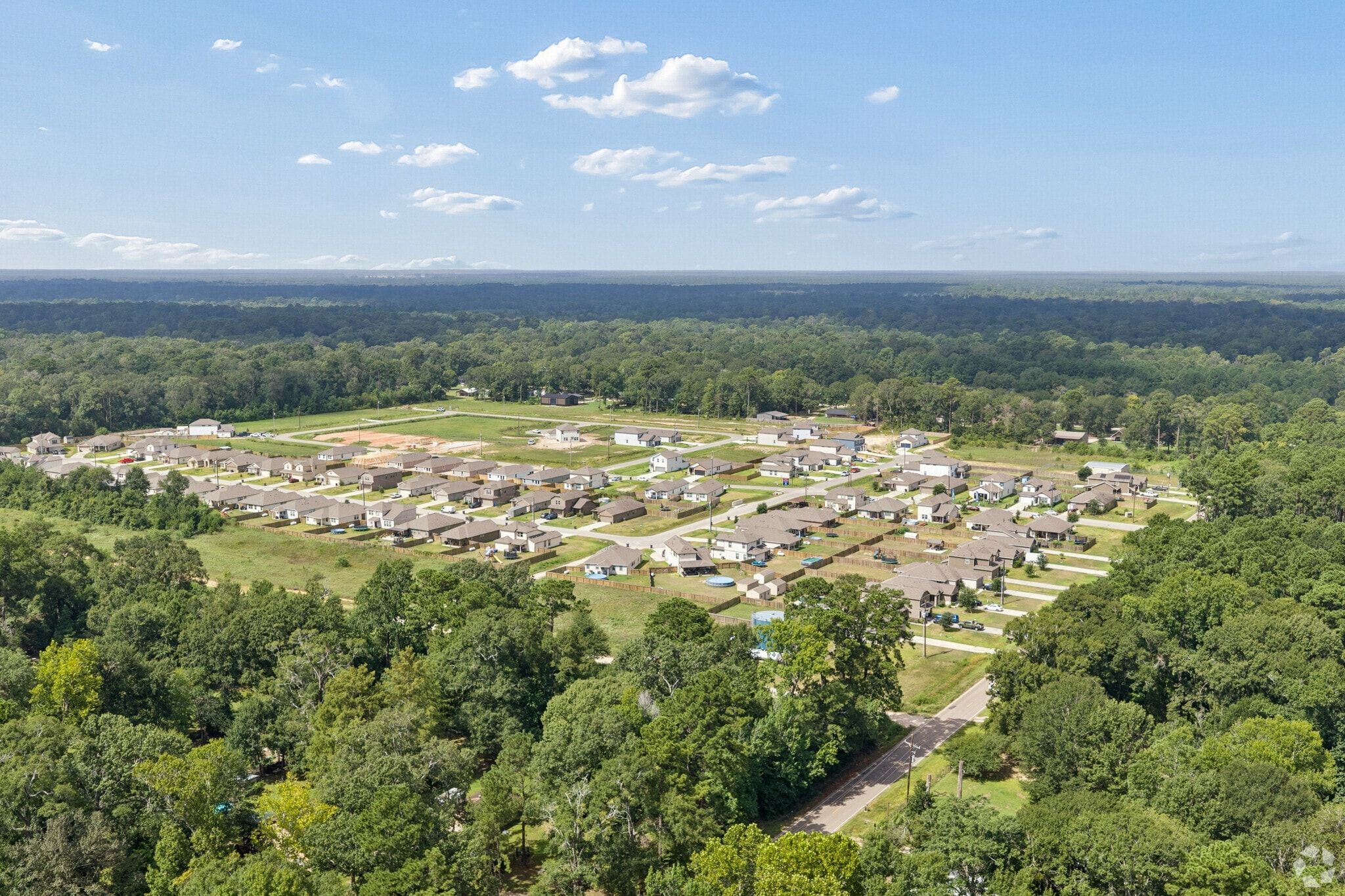 Aerial view of Liberty Estates community in Cleveland, Texas, featuring new homes built by Davidson Homes among wooded areas.
