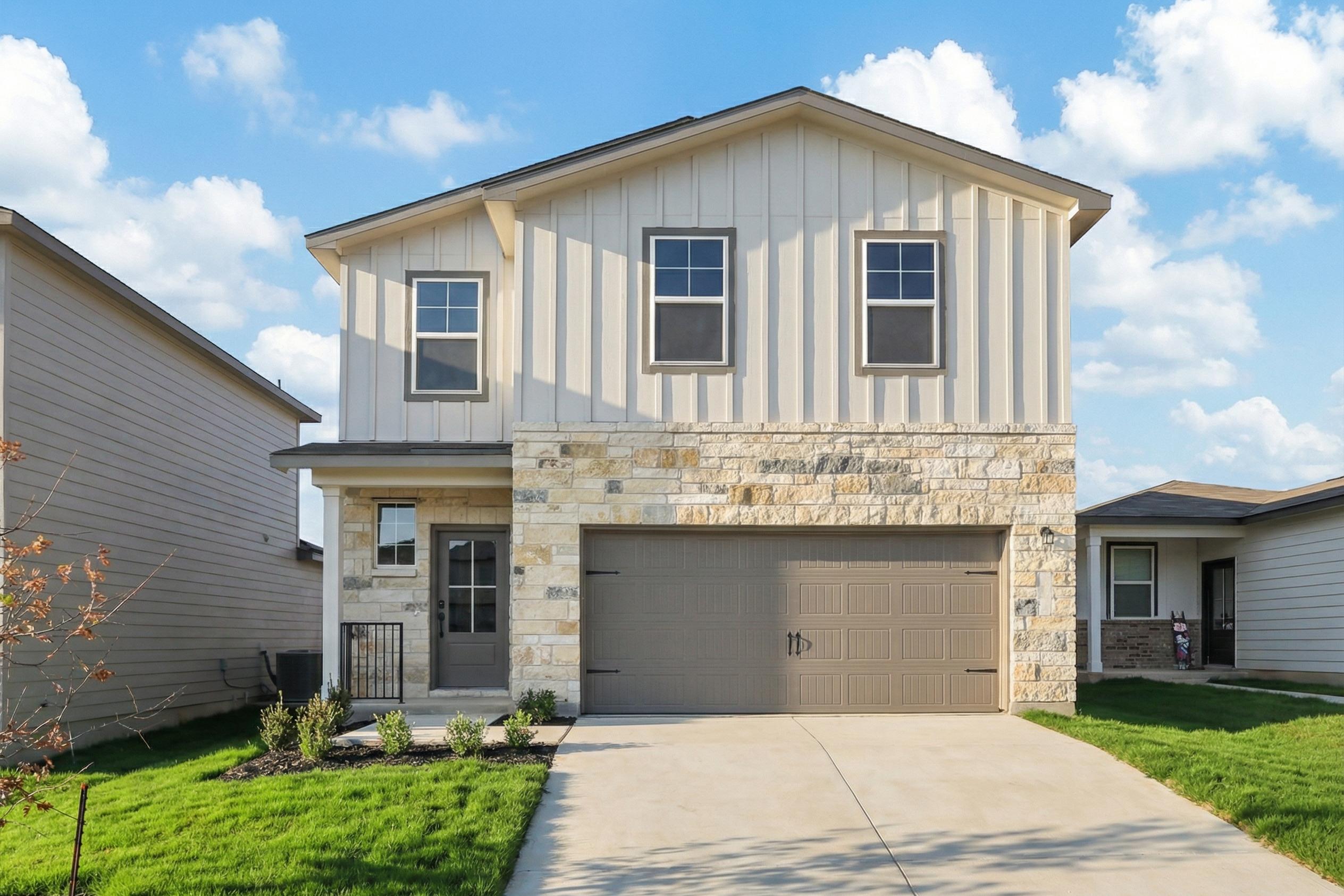 Modern two-story home exterior at Applewhite Meadows in San Antonio Texas with white siding stone accents covered porch and garage
