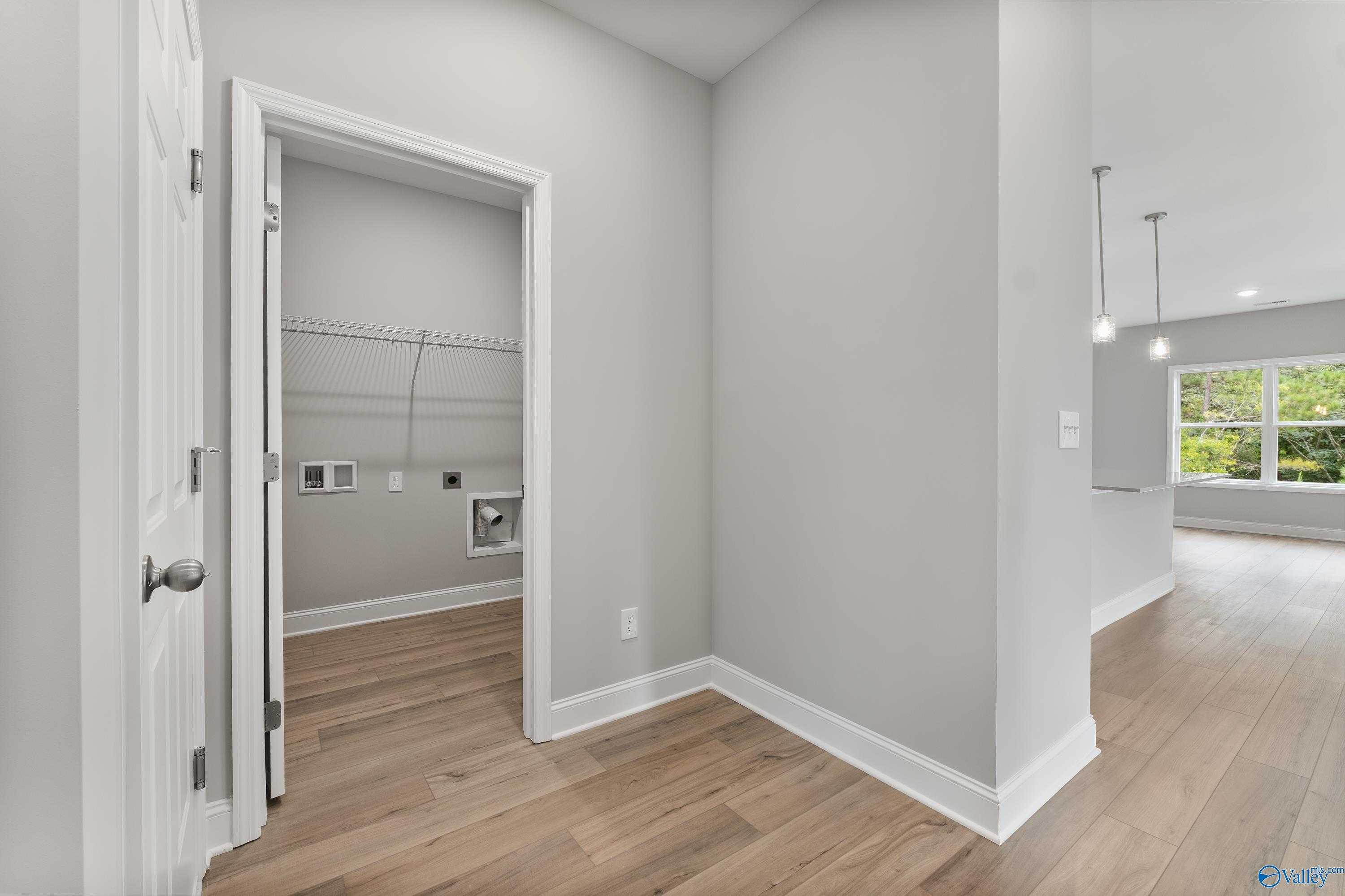 Modern laundry room with washer/dryer hookups, open shelving, gray walls, and hardwood floors in Davidson Homes The Franklin, Huntsville