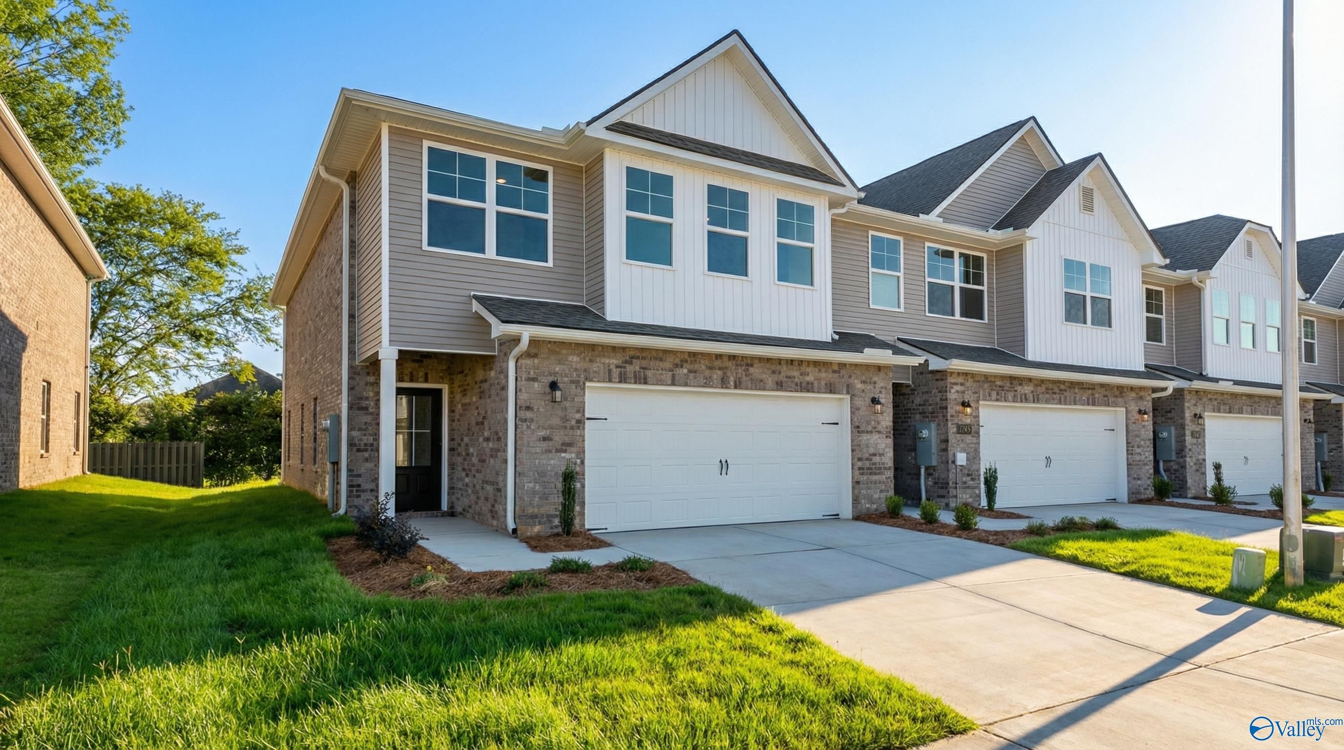 Two-story Camden home exterior by Davidson Homes in Pavilion, Huntsville, AL: beige siding, brick accents, two-car garage, landscaped yard