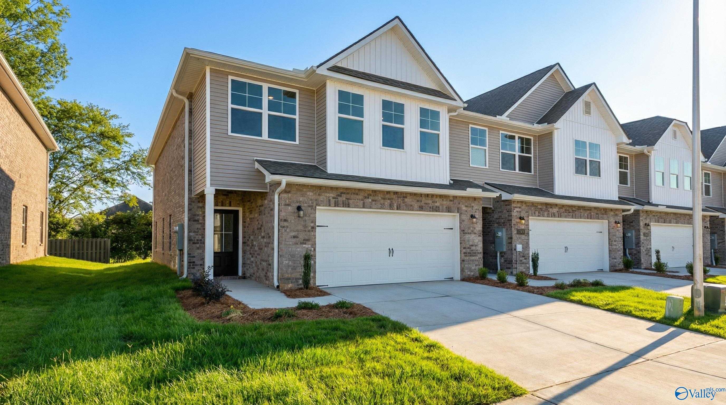 Two-story Camden home exterior by Davidson Homes in Pavilion, Huntsville, AL: beige siding, brick accents, two-car garage, landscaped yard