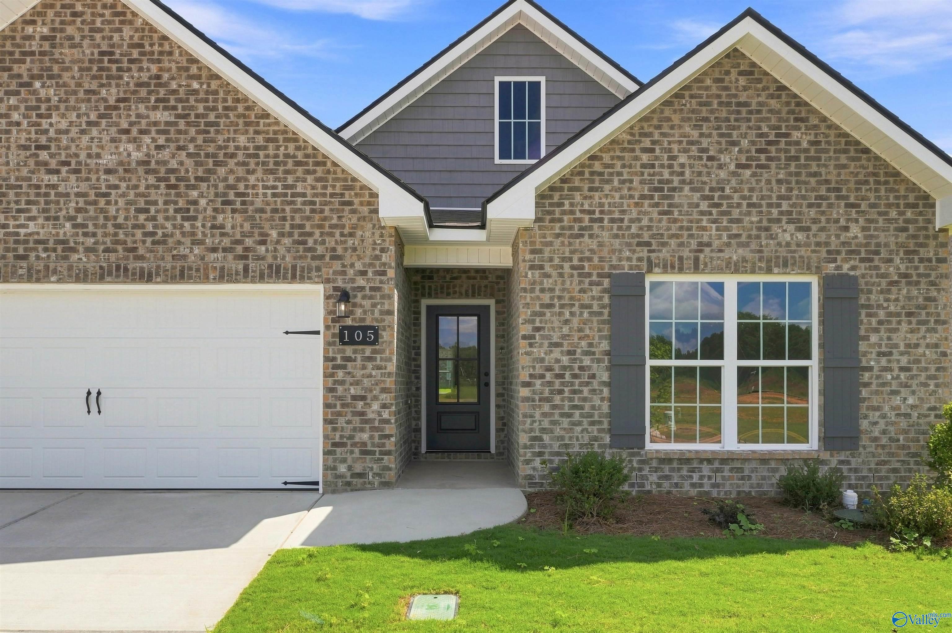 Brick front exterior with 2-car garage and black front door at Davidson Homes' The Franklin C in Wood Trail, Toney, Alabama
