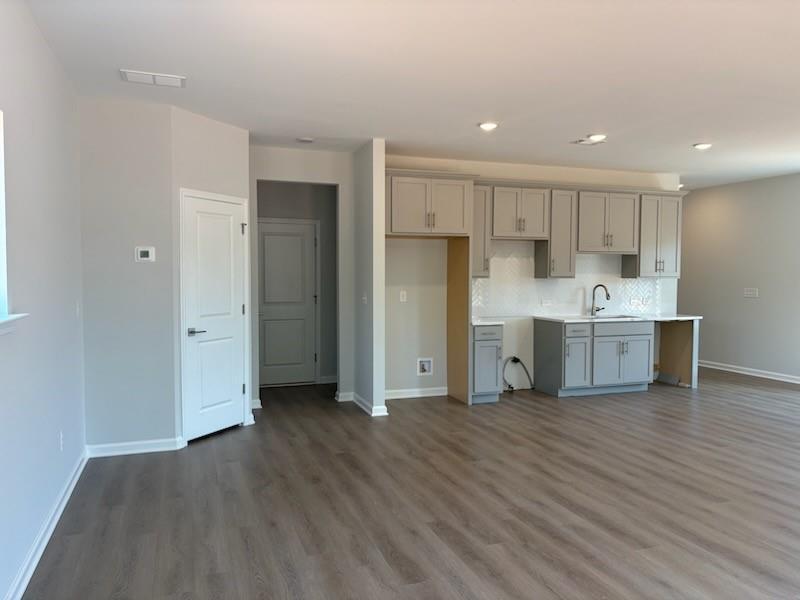 Modern open kitchen with gray shaker cabinets, white quartz counters, tile backsplash in The Rabun A floor plan, Winder GA
