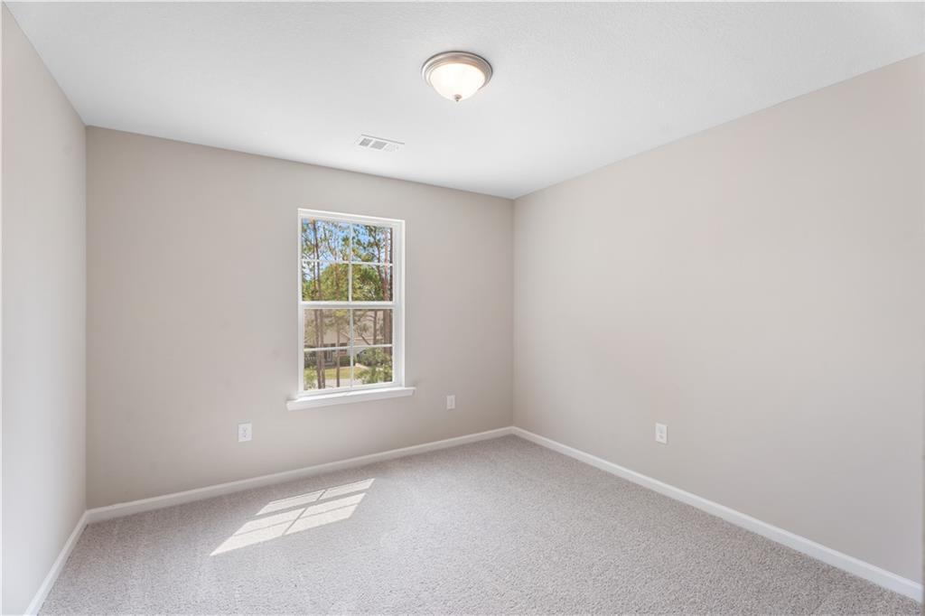 Bright secondary bedroom with beige walls, large sunny window, carpeted floor in Evermore Homes The Washington, Phenix City, AL