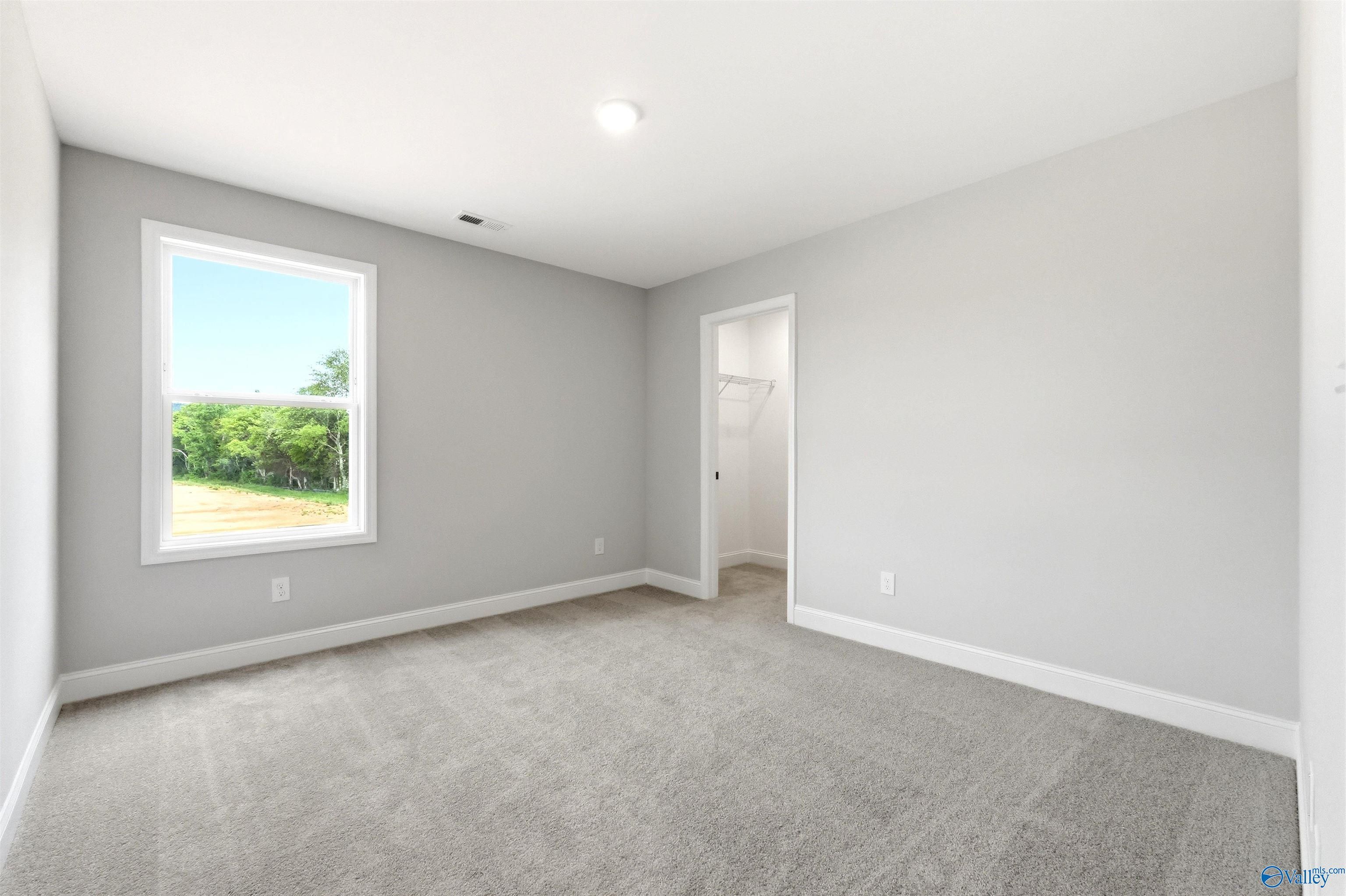 Bright, carpeted bedroom with walk-in closet in The Chelsea D floor plan at Berry Cove, New Market, Alabama.