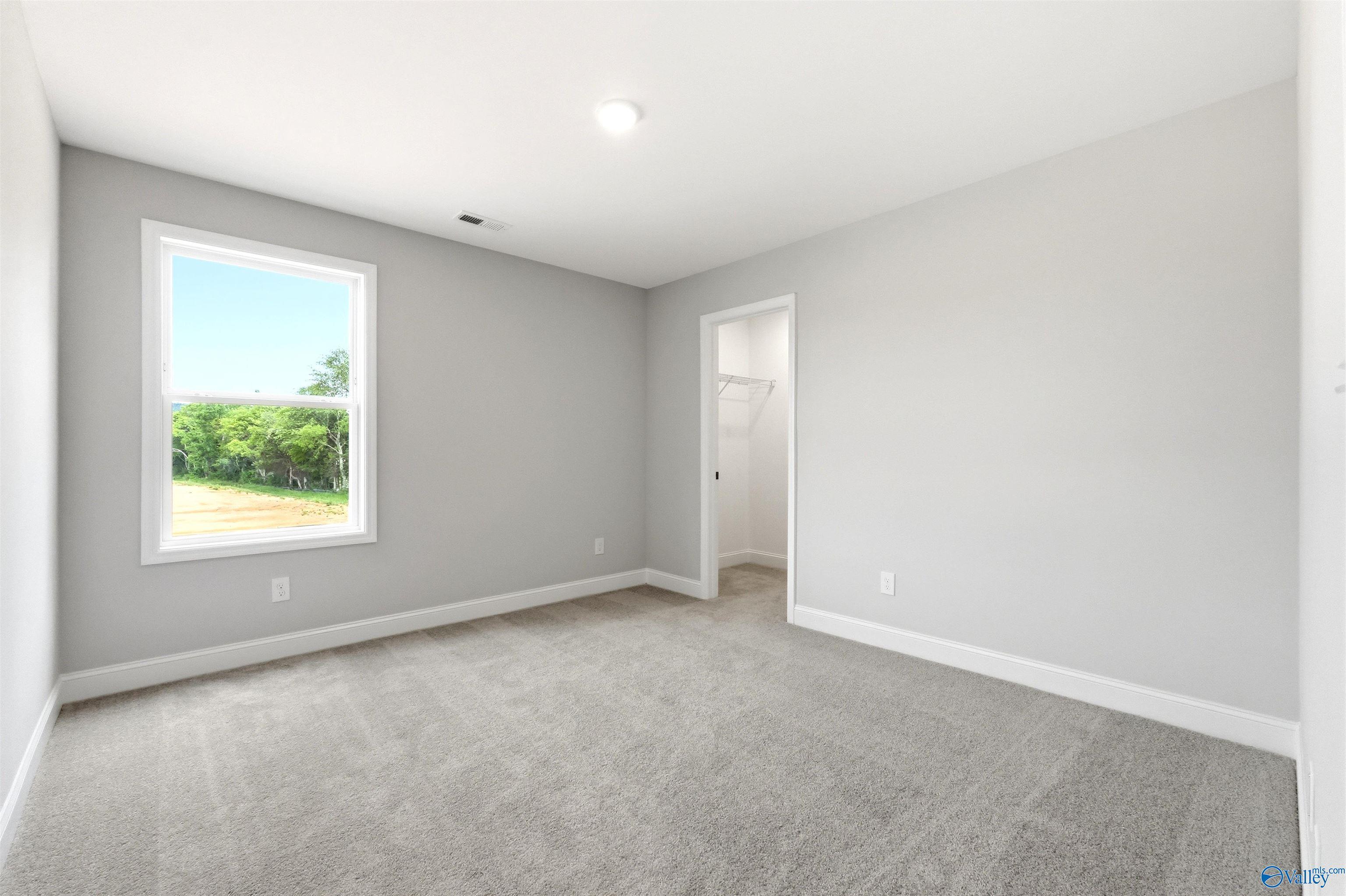 Bright, carpeted bedroom with walk-in closet in The Chelsea D floor plan at Berry Cove, New Market, Alabama.