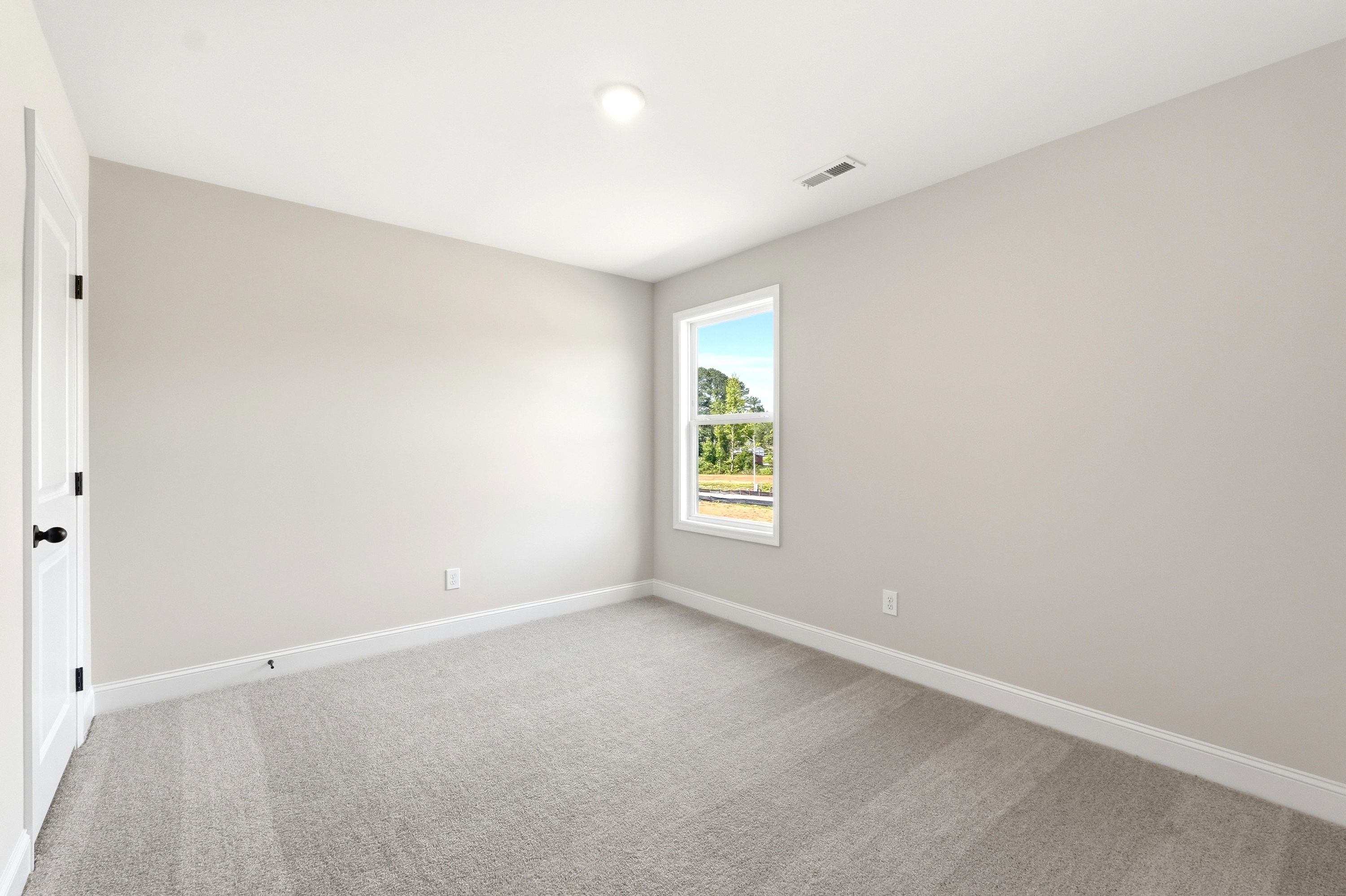 Spacious secondary bedroom with neutral carpet and paint in The Russell A floor plan by Davidson Homes.