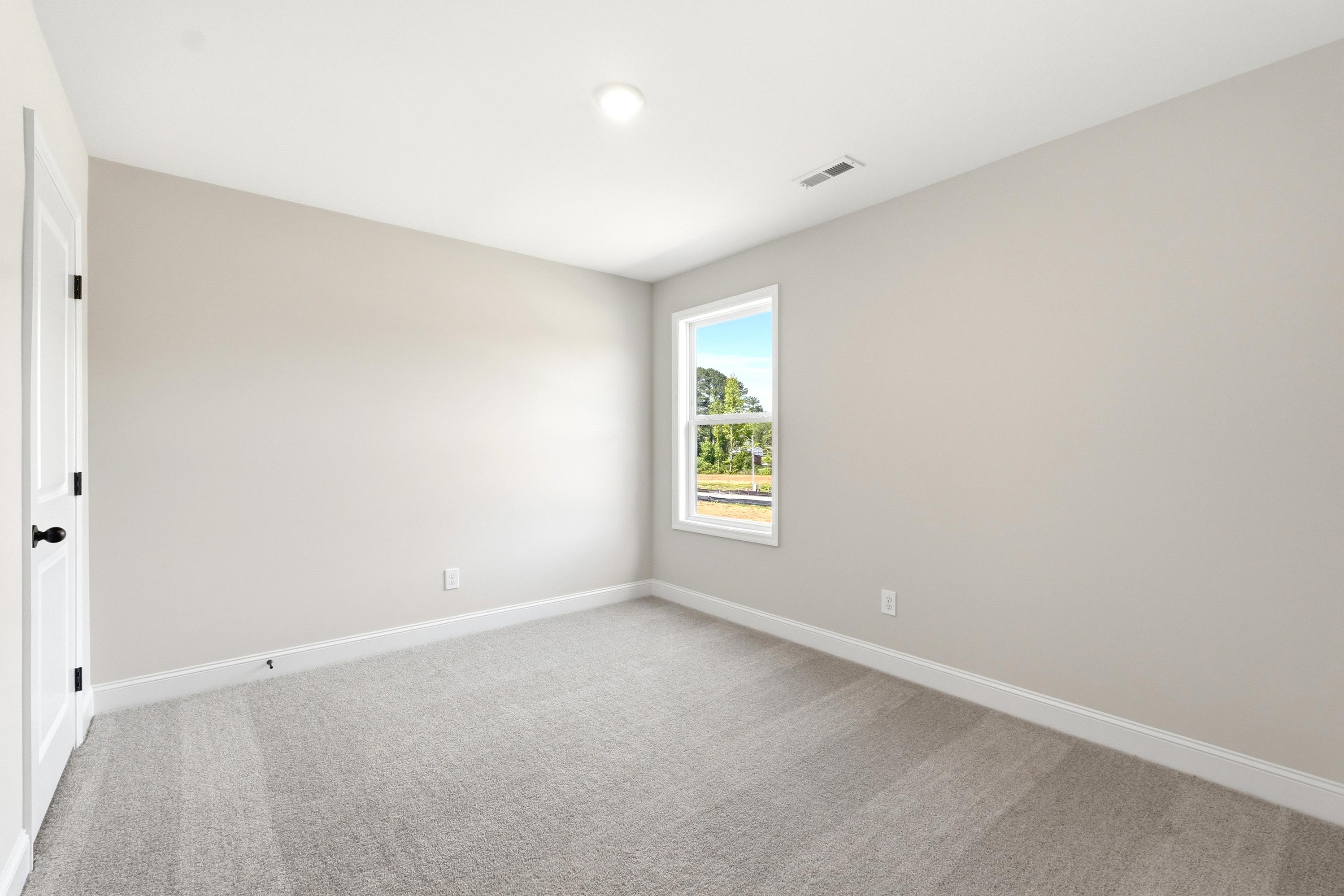 Spacious secondary bedroom with neutral carpet and paint in The Russell A floor plan by Davidson Homes.