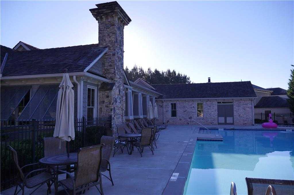 Resort-style community pool with lounge chairs, umbrellas, and stone townhomes in The Village at Towne Lake, Woodstock, Georgia