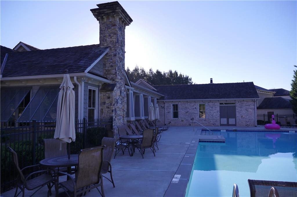 Resort-style community pool with lounge chairs, umbrellas, and stone townhomes in The Village at Towne Lake, Woodstock, Georgia