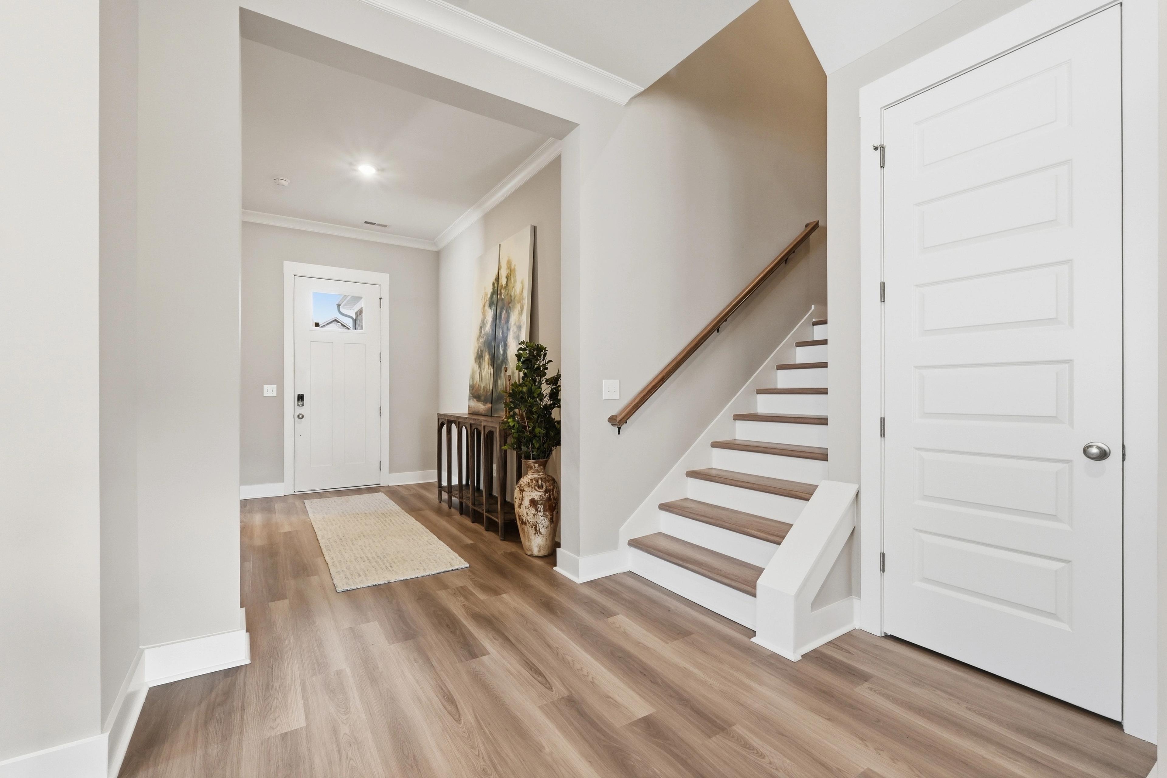 Spacious entryway at The Meadows at Hampton Cove in Owens Cross Roads AL with hardwood floors, staircase, and artwork