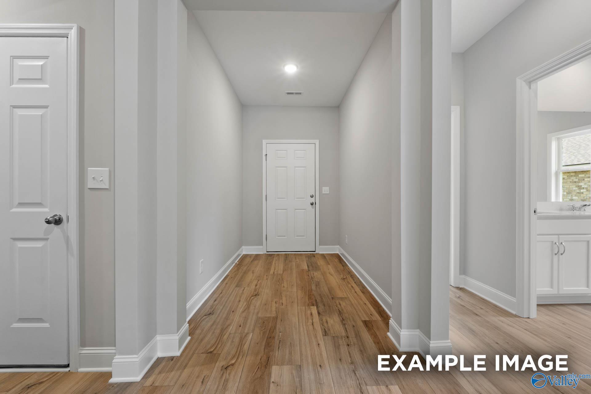 Spacious hallway with hardwood floors, white doors, and neutral walls in Davidson Homes The Everett B, Athens AL