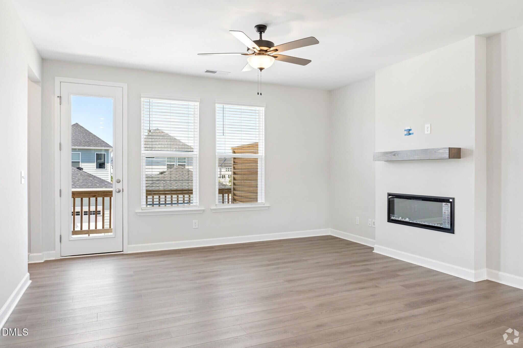 Bright living room with electric fireplace, ceiling fan, and glass door to deck in Davidson Homes The Mitchell, Knightdale NC
