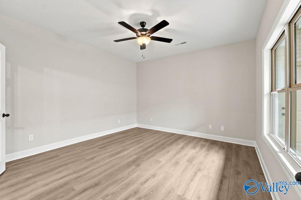Spacious bedroom with wood-look flooring and ceiling fan in The Camilla C floor plan at The Retreat at Cain Park, Hartselle.