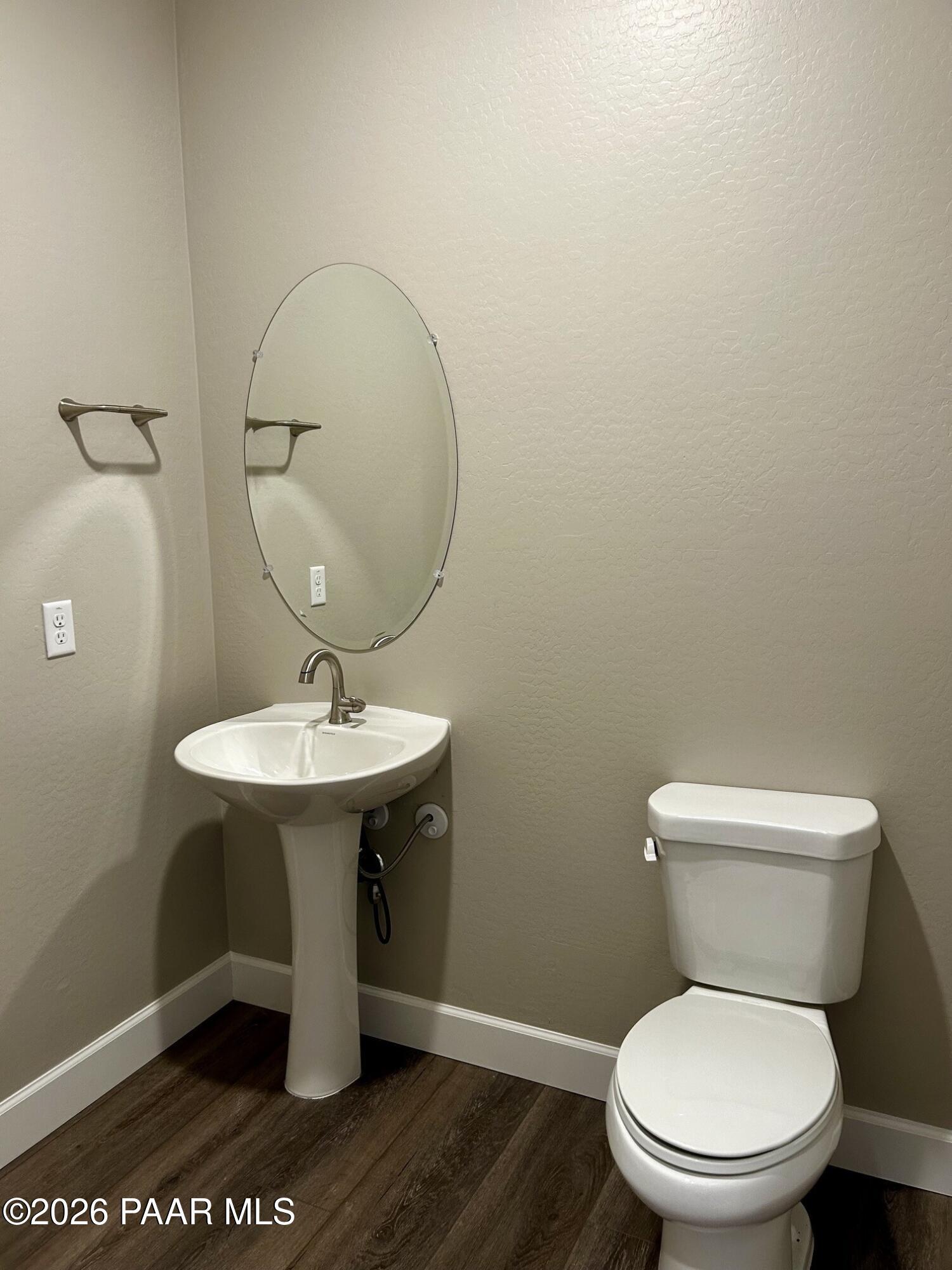 Half bathroom with pedestal sink, oval mirror, and toilet in The Harmony C floor plan at North Ridge, Prescott Valley.