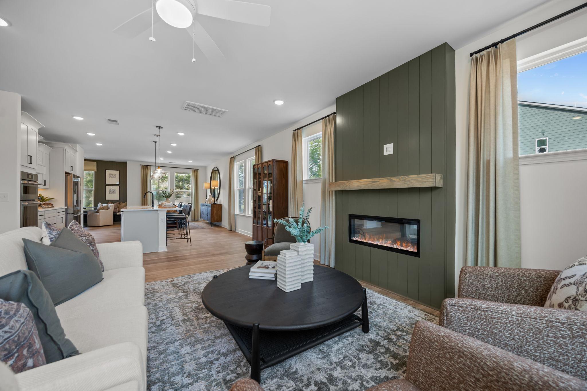 Spacious open-concept living room in Camden Park Knightdale NC with green accent wall, linear gas fireplace, hardwood floors