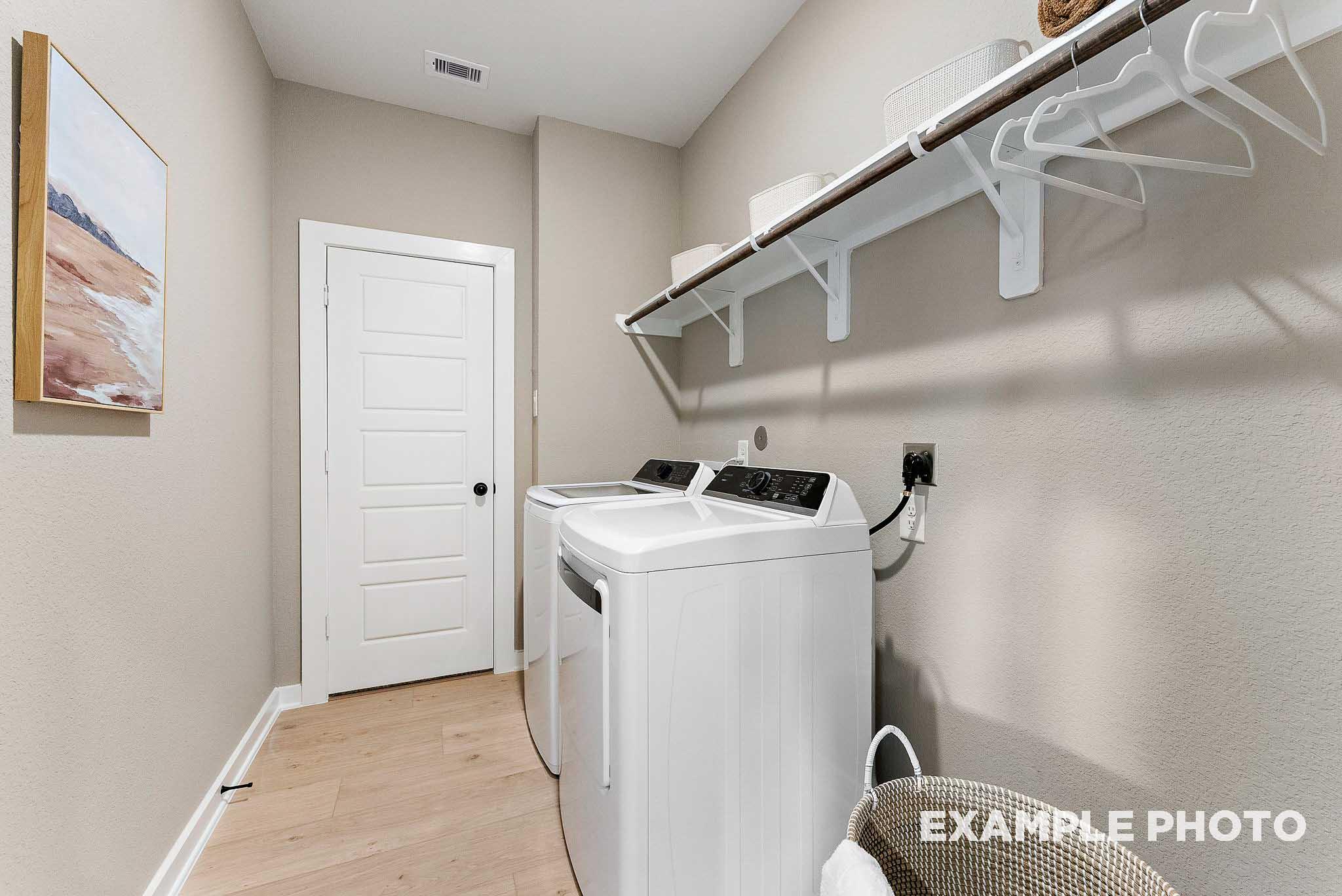 Laundry room with washer and dryer, shelving, and hanging rack in The Everett E floor plan at Sundance Cove, Crosby, TX.