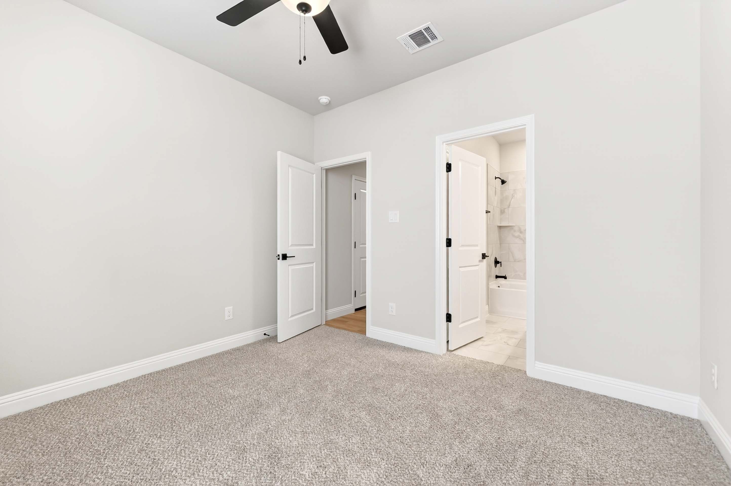 Spacious bedroom in The Holly home design featuring plush carpeting and a private en-suite bathroom with modern finishes.