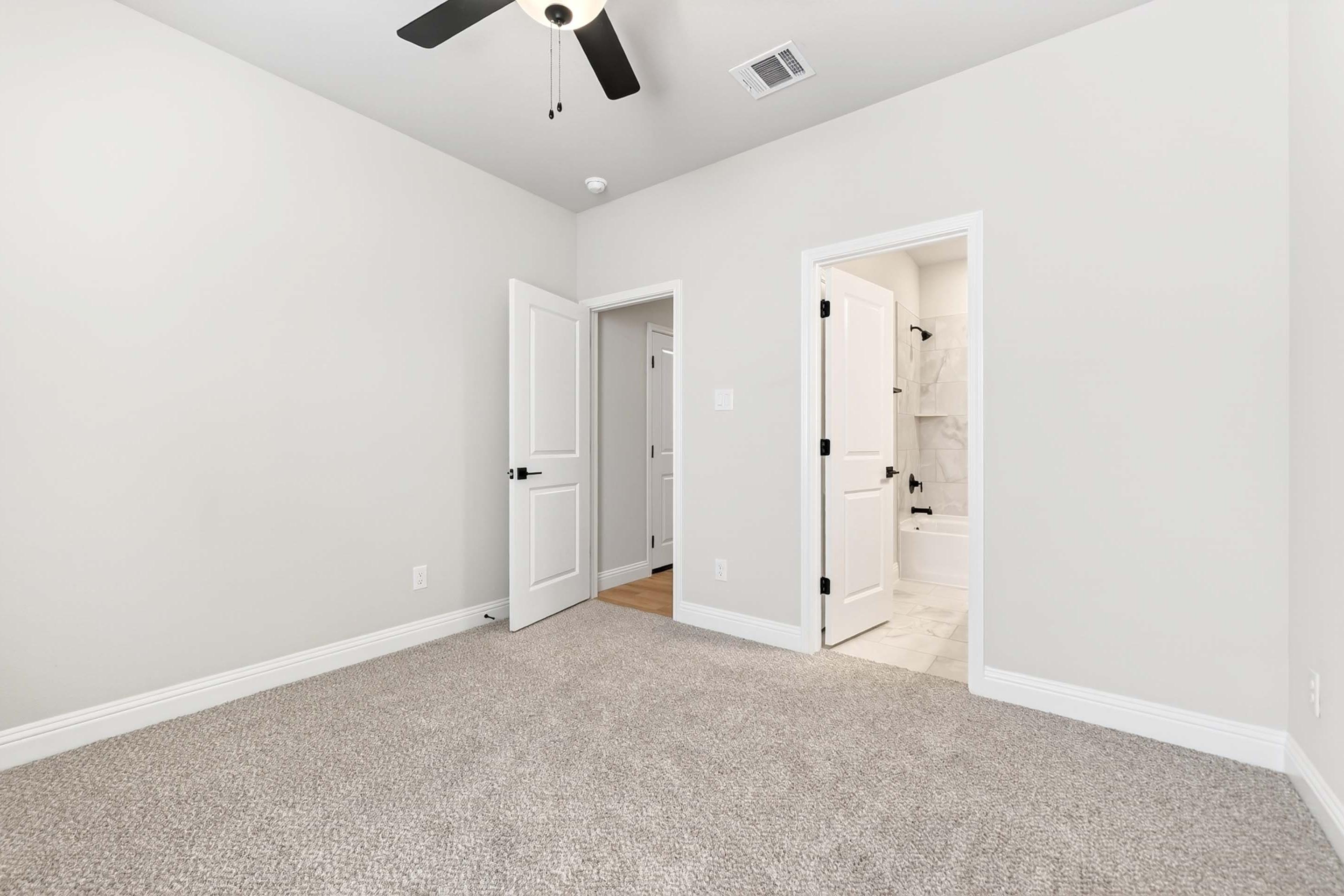 Spacious bedroom in The Holly home design featuring plush carpeting and a private en-suite bathroom with modern finishes.