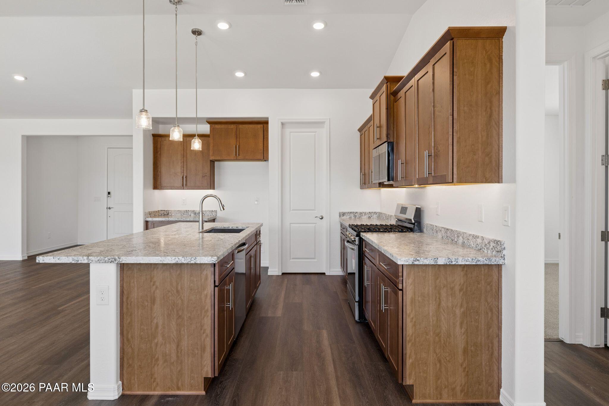 Modern kitchen with granite countertops, stainless steel appliances, wooden cabinets, and center island in Davidson Homes The Monarch A, Prescott, AZ