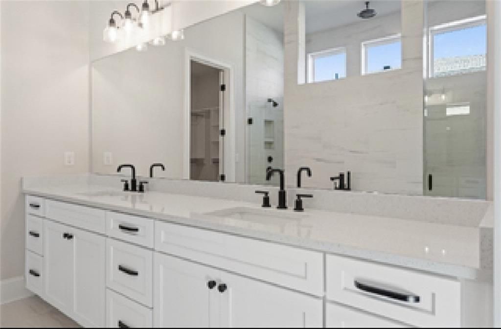 Elegant master bathroom with double white vanity, black faucets, quartz counters, and glass shower in Davidson Homes Seaside A, Woodstock GA