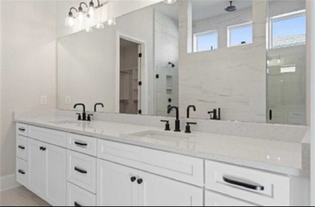 Elegant master bathroom with double white vanity, black faucets, quartz counters, and glass shower in Davidson Homes Seaside A, Woodstock GA
