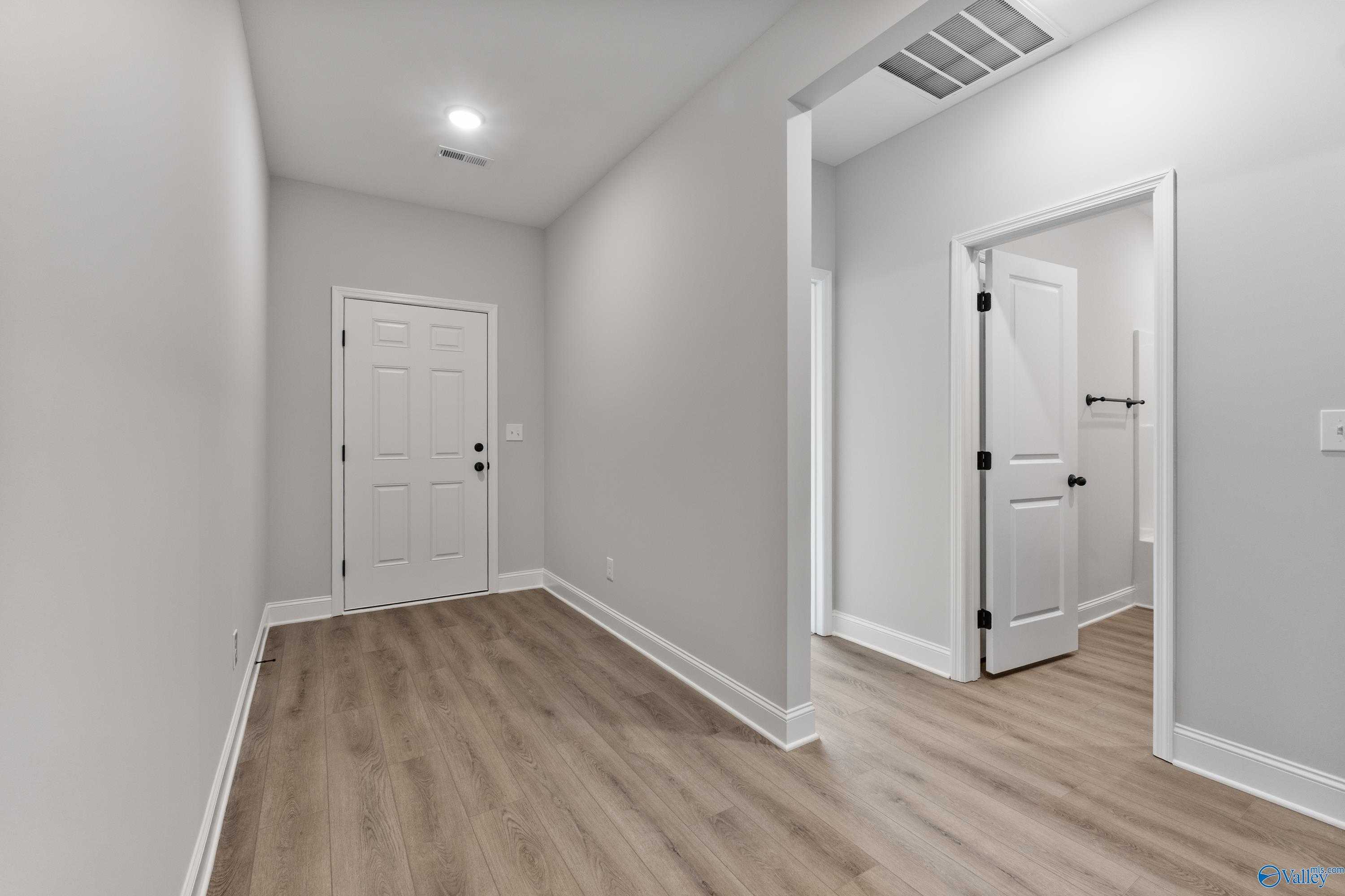 Spacious hallway with light oak floors, gray walls, and doors to bedrooms and bath in The Daphne floor plan, Huntsville AL