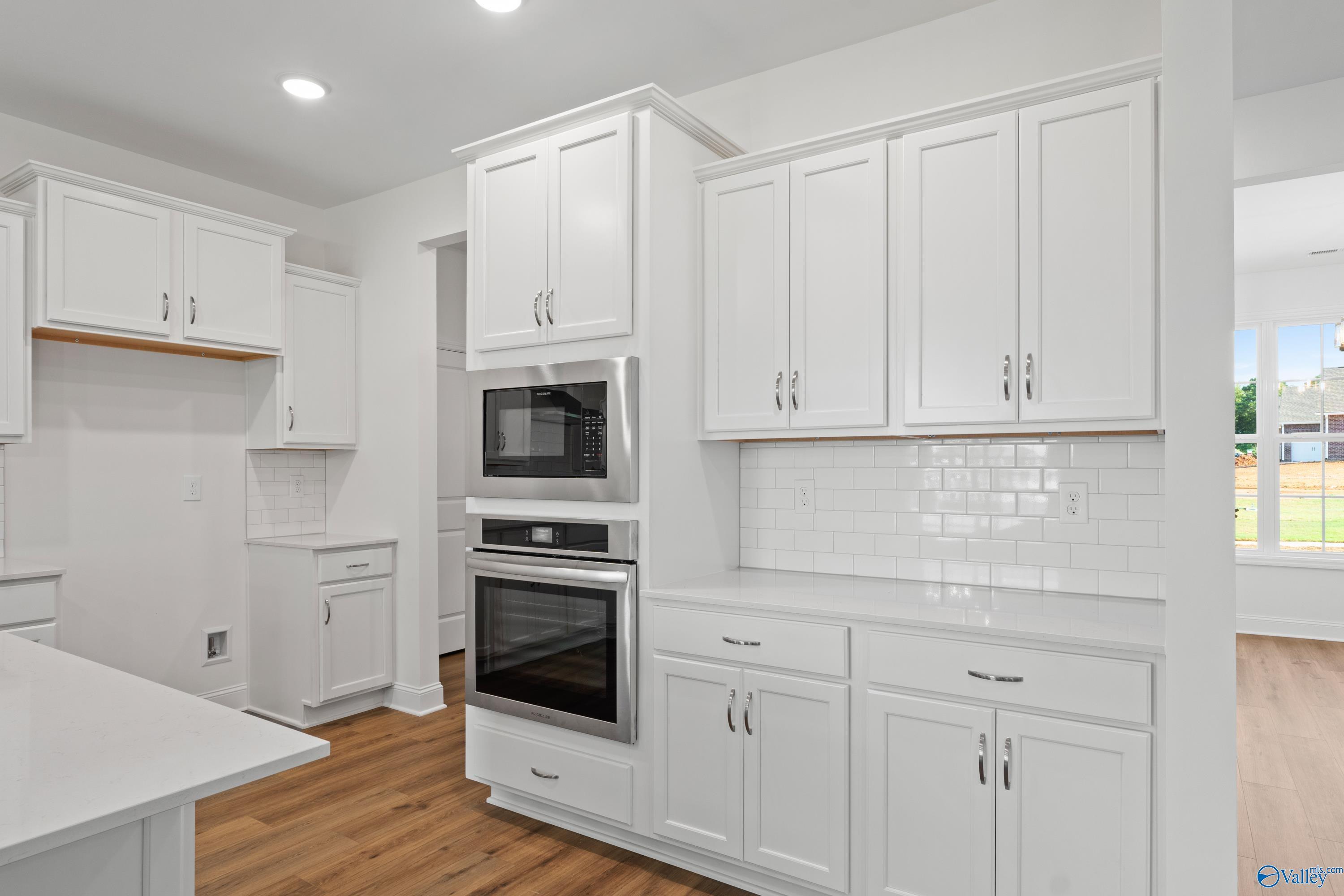 Modern white kitchen with stainless double oven, subway tile backsplash, and quartz counters in Davidson Homes The Oxford, Harvest, AL
