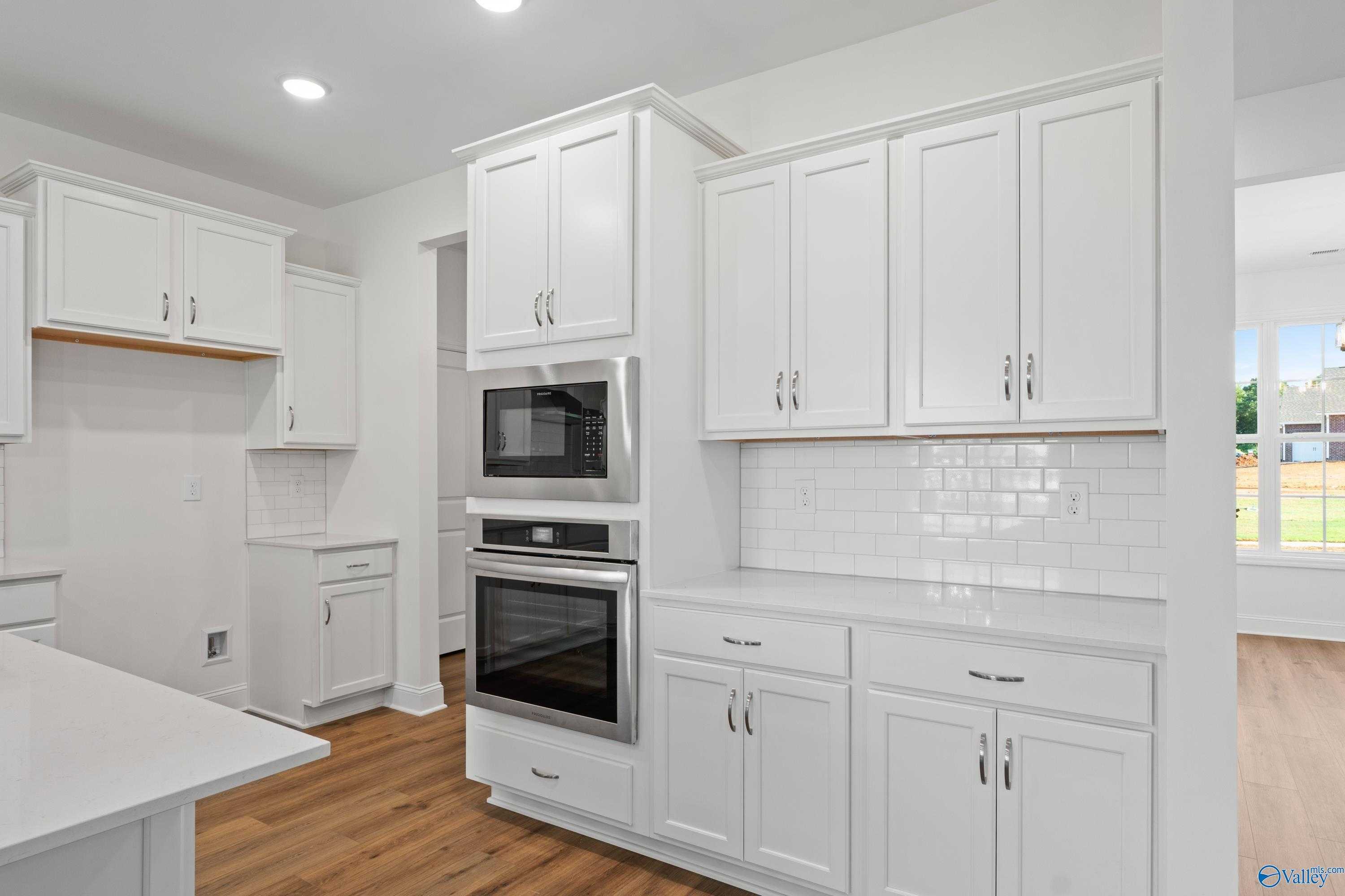 Modern white kitchen with stainless double oven, subway tile backsplash, and quartz counters in Davidson Homes The Oxford, Harvest, AL