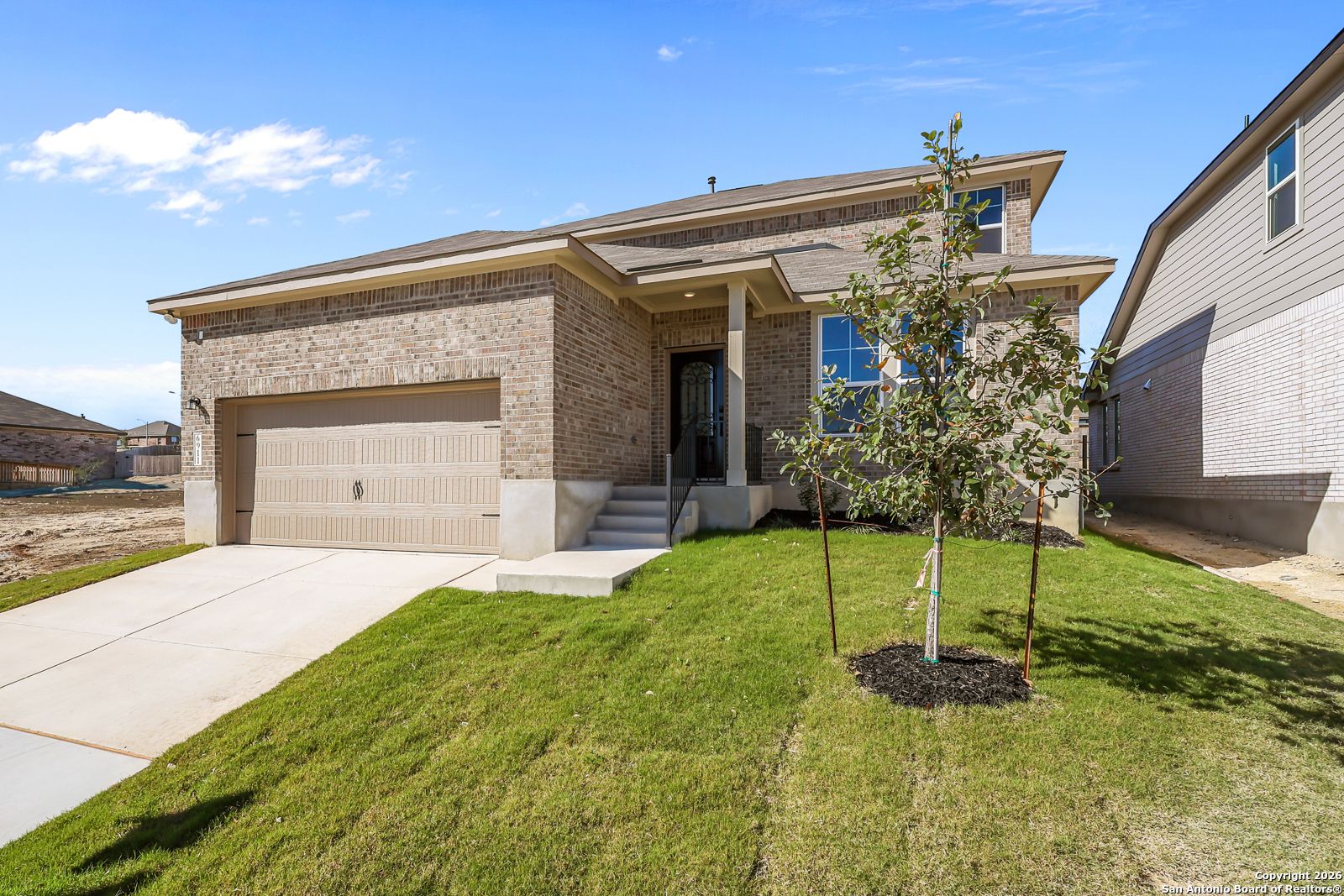 Brick two-story home with 2-car garage, front porch, and lush lawn in Comanche Ridge, San Antonio, Texas by Davidson Homes The Douglas E