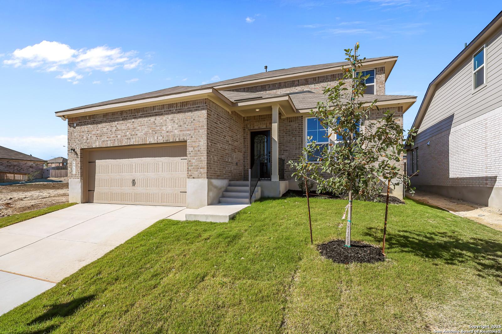 Brick two-story home with 2-car garage, front porch, and lush lawn in Comanche Ridge, San Antonio, Texas by Davidson Homes The Douglas E