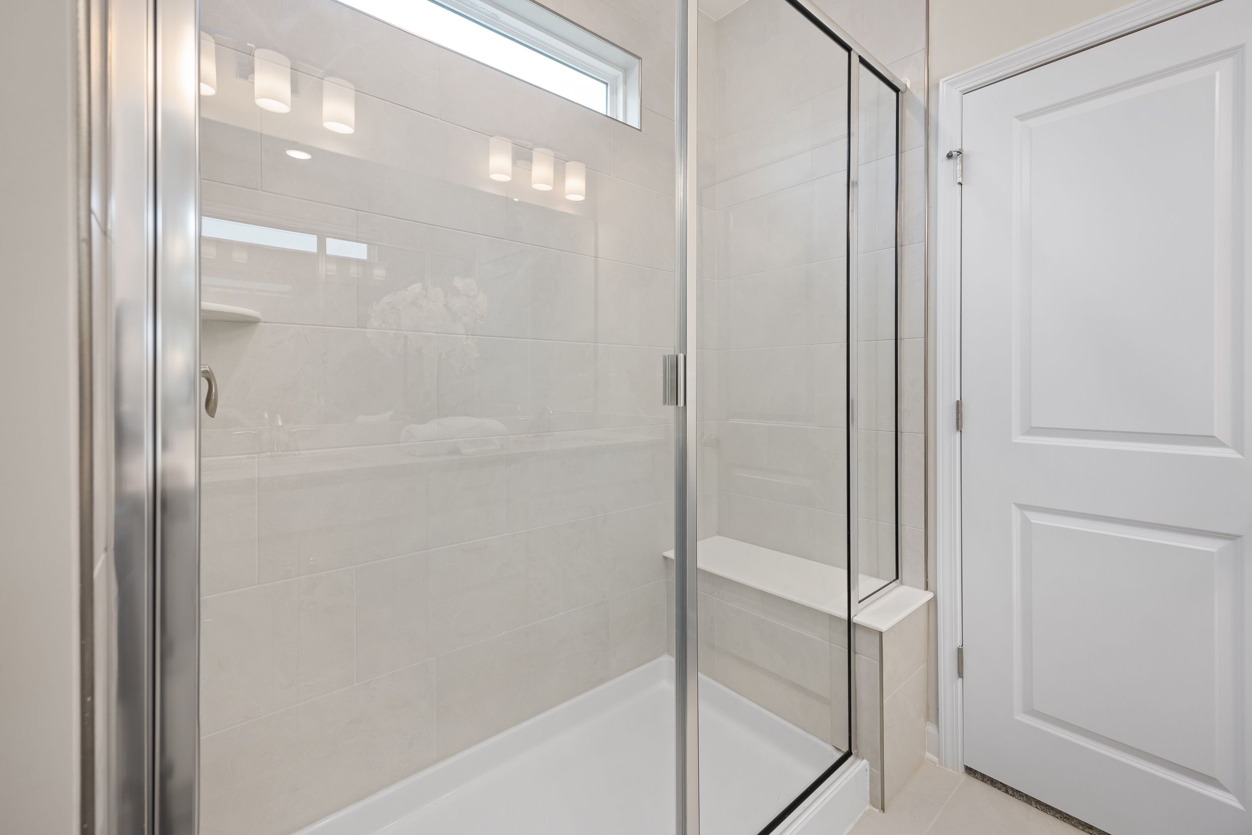 Walk-in tile shower with glass enclosure and built-in bench at Gregory Village in Lillington, NC by Davidson Homes.