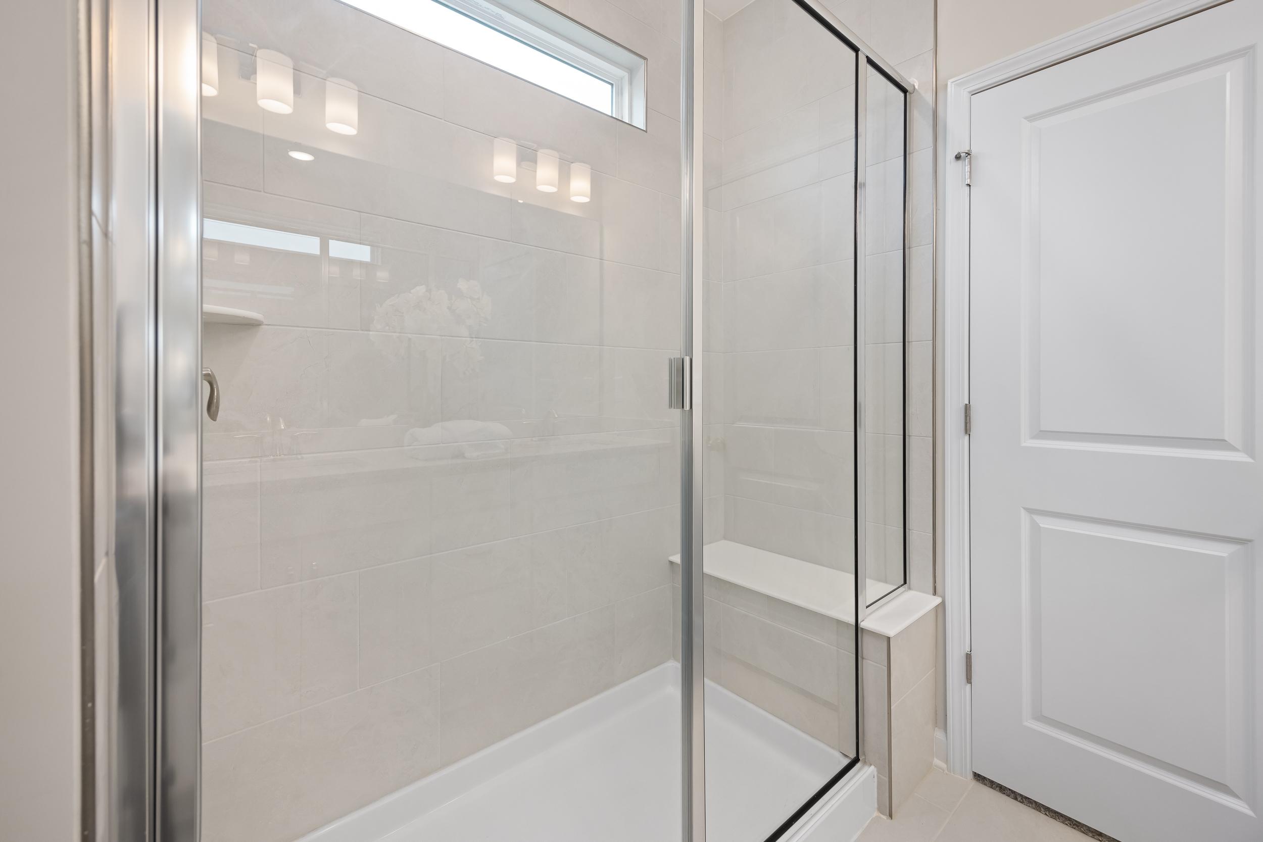 Walk-in tile shower with glass enclosure and built-in bench at Gregory Village in Lillington, NC by Davidson Homes.