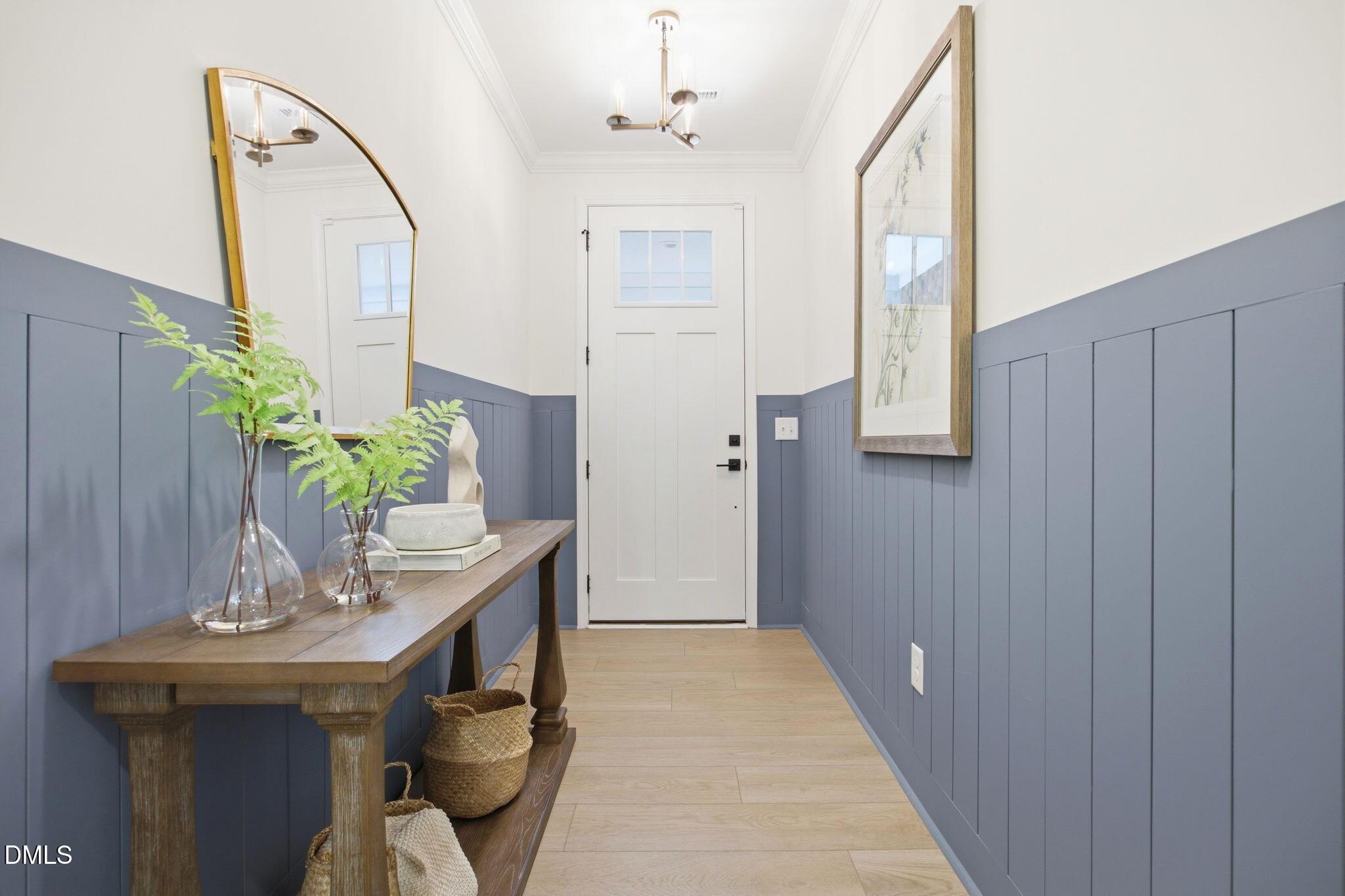Foyer with blue board and batten wainscoting and wooden console table in The Ashport M home at Wendell Ridge, NC.