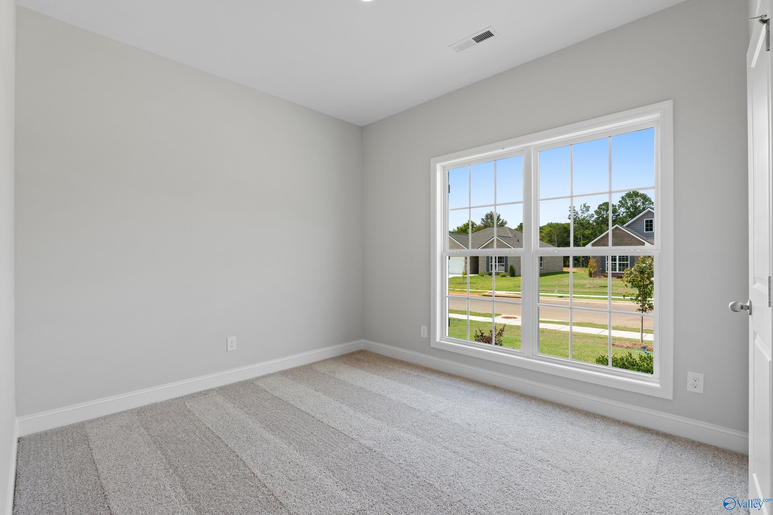 Bright empty bedroom with gray carpet, large window overlooking Spragins Cove neighborhood in Davidson Homes Asheville, Huntsville AL